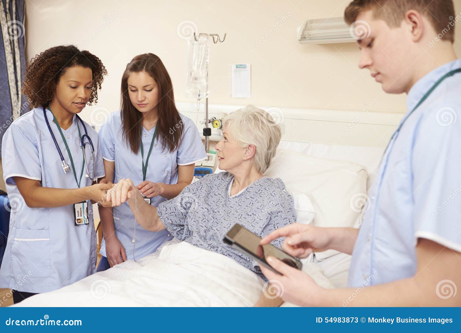 trainee nursing staff by female patient's bed in hospital