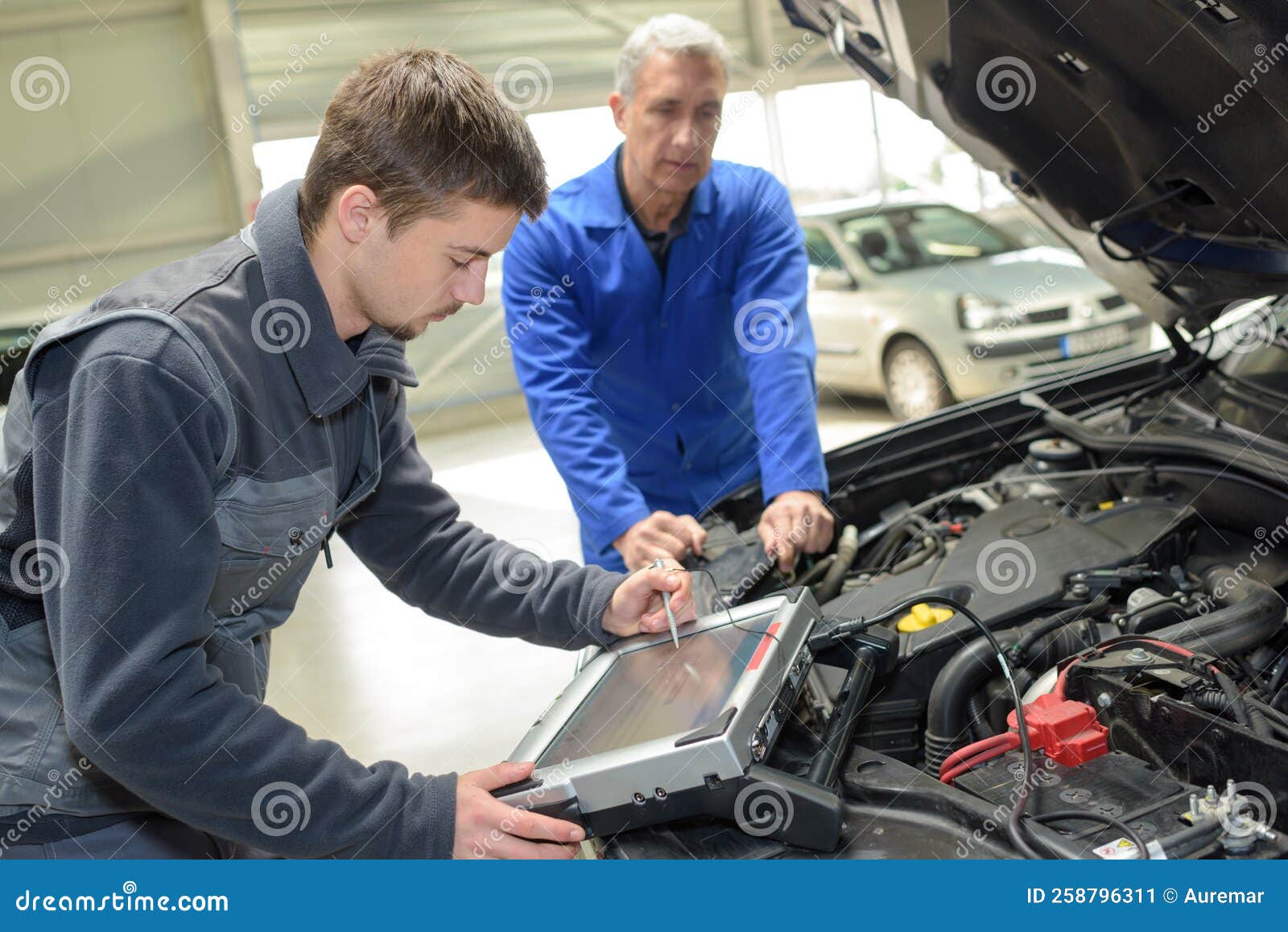 Trainee Testing Car Electronics with Computer in Professional Garage