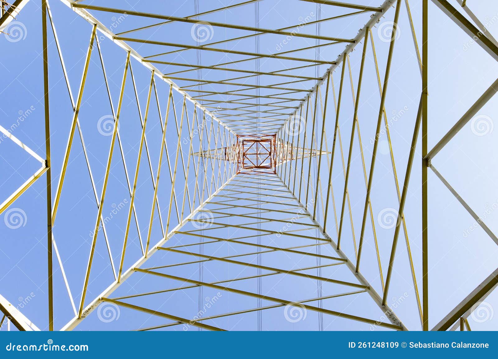 electricity pylon in perspective seen from below with blue sky background