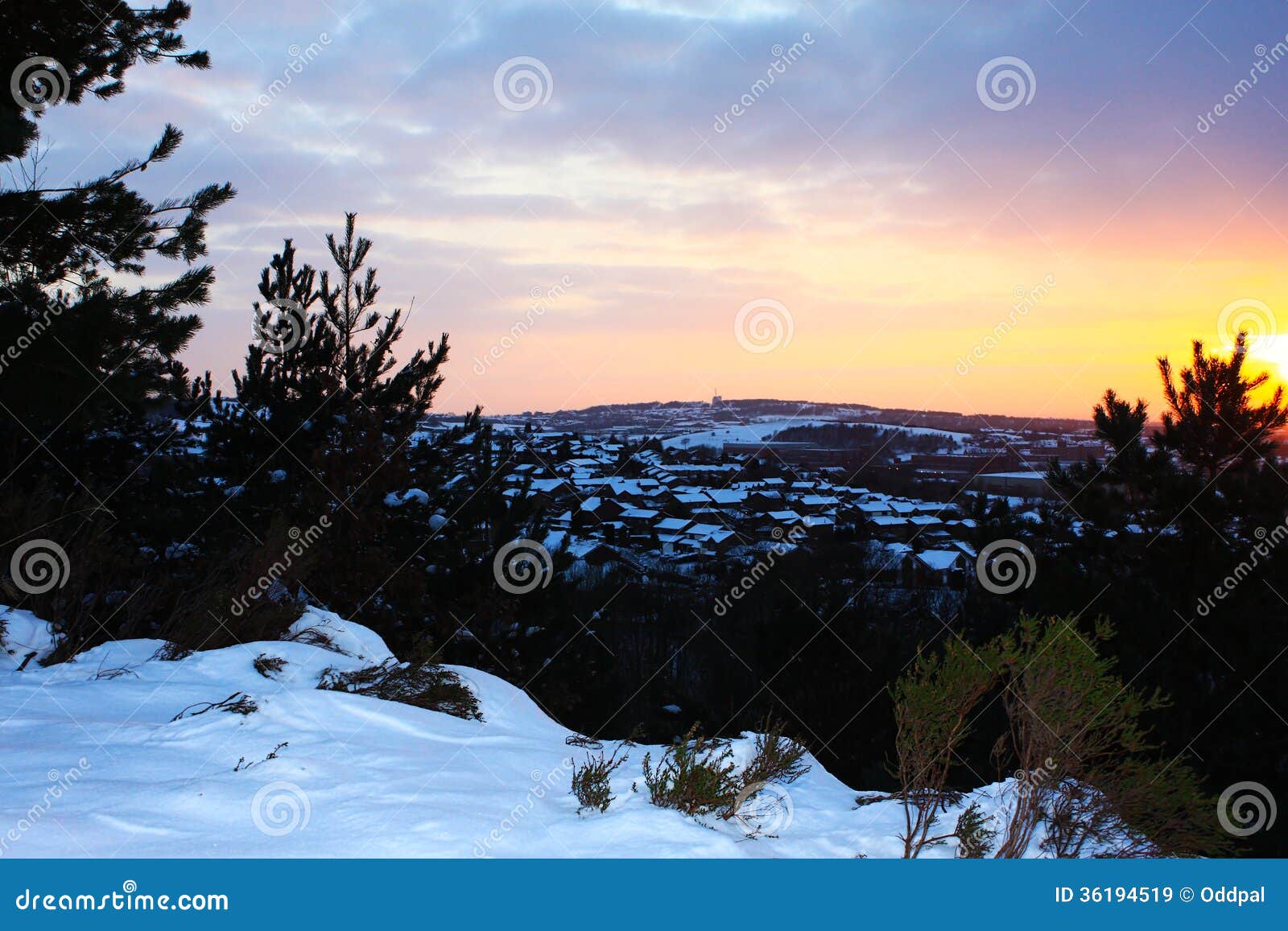 Tramonto di inverno sopra la città nevosa. Paesaggio di tramonto di inverno delle colline innevate delle pennine intorno a Manchester con i tetti della città di Rochdale nella distanza.