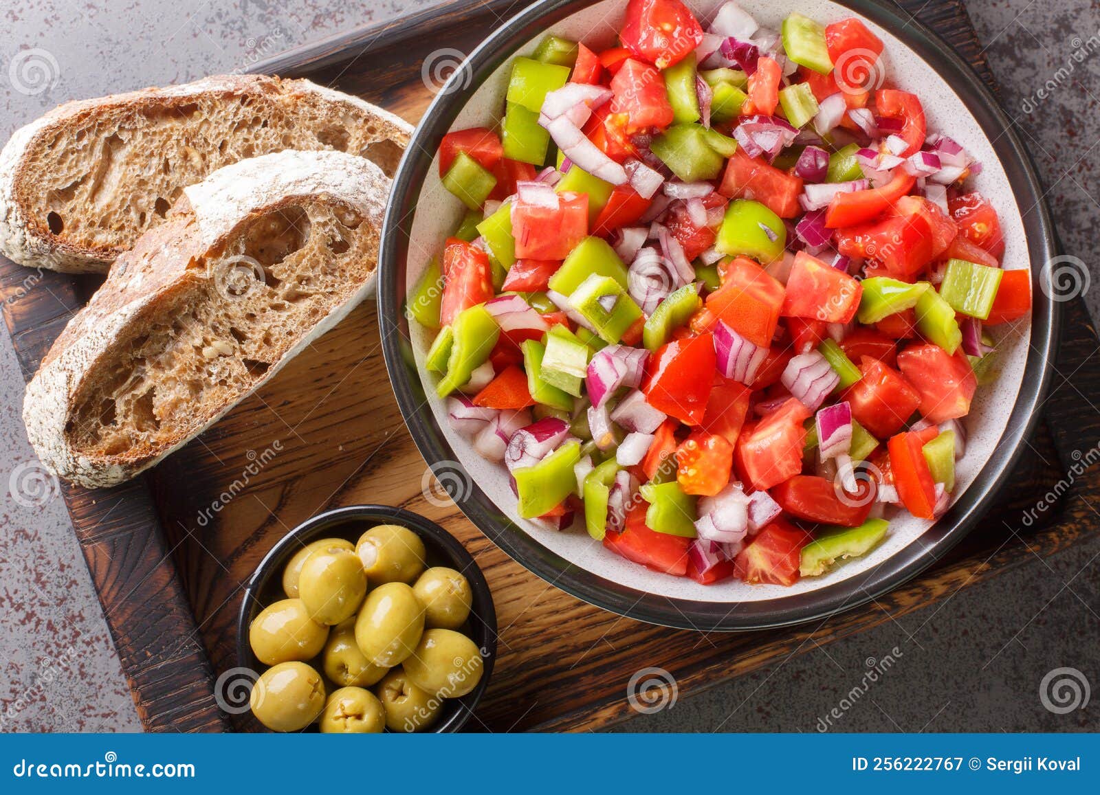trampo ensalada salad made with tomatoes, peppers, and onions served with olive and bread closeup on the wooden board. horizontal