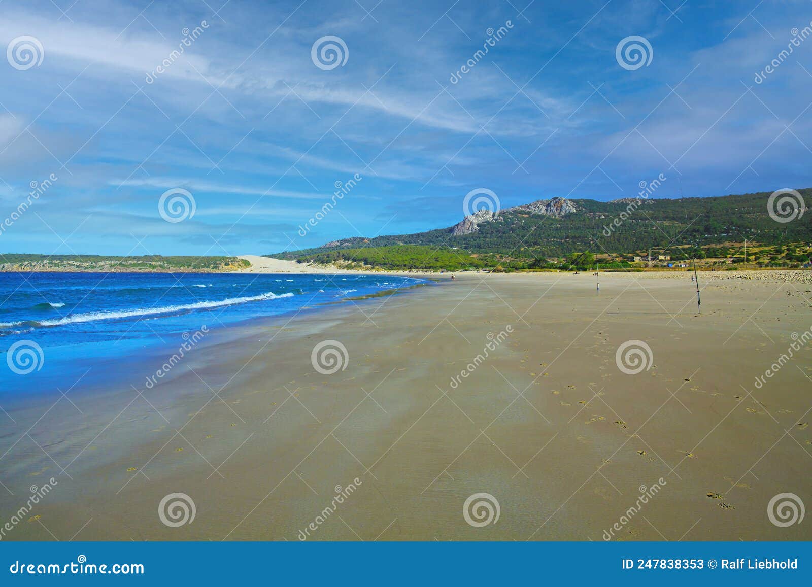 tranquil morning empty sand beach scene, low tide, natural green hills, blue sky - zahara de los atunes, costa de la luz, spain