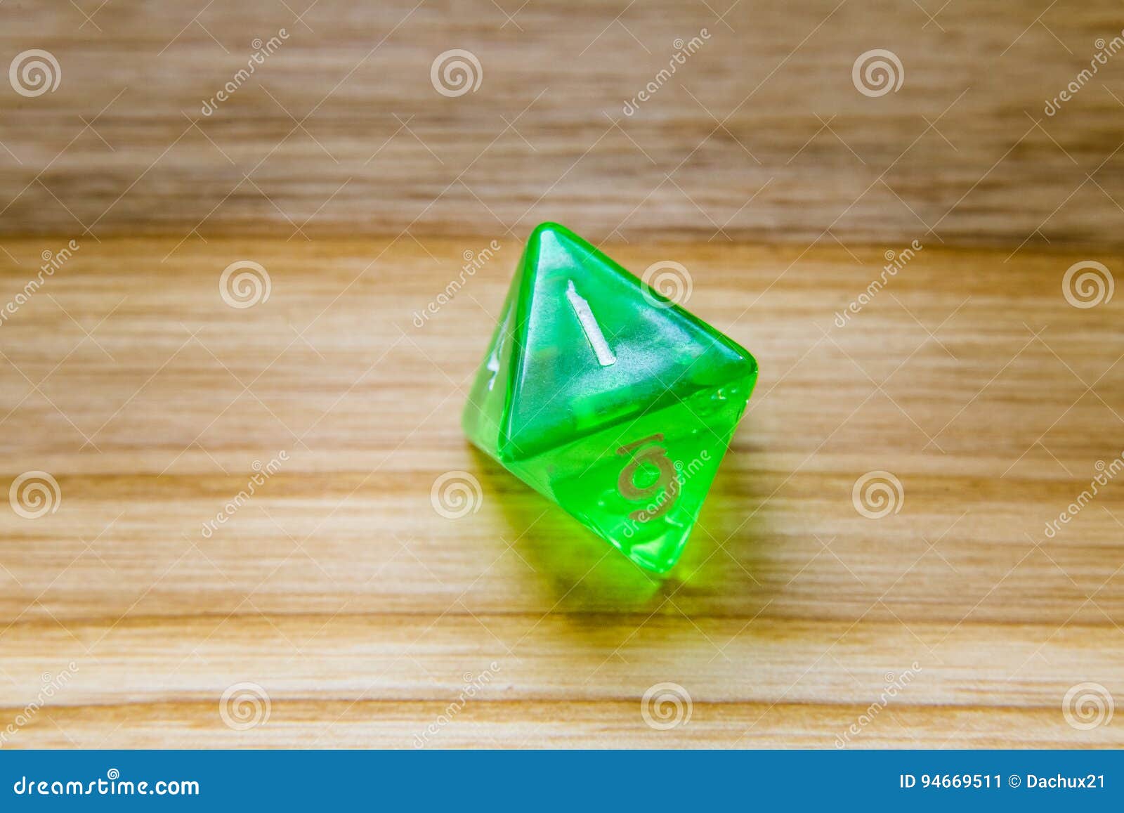 a translucent green eight sided playing dice on a wooden background with number one on a top