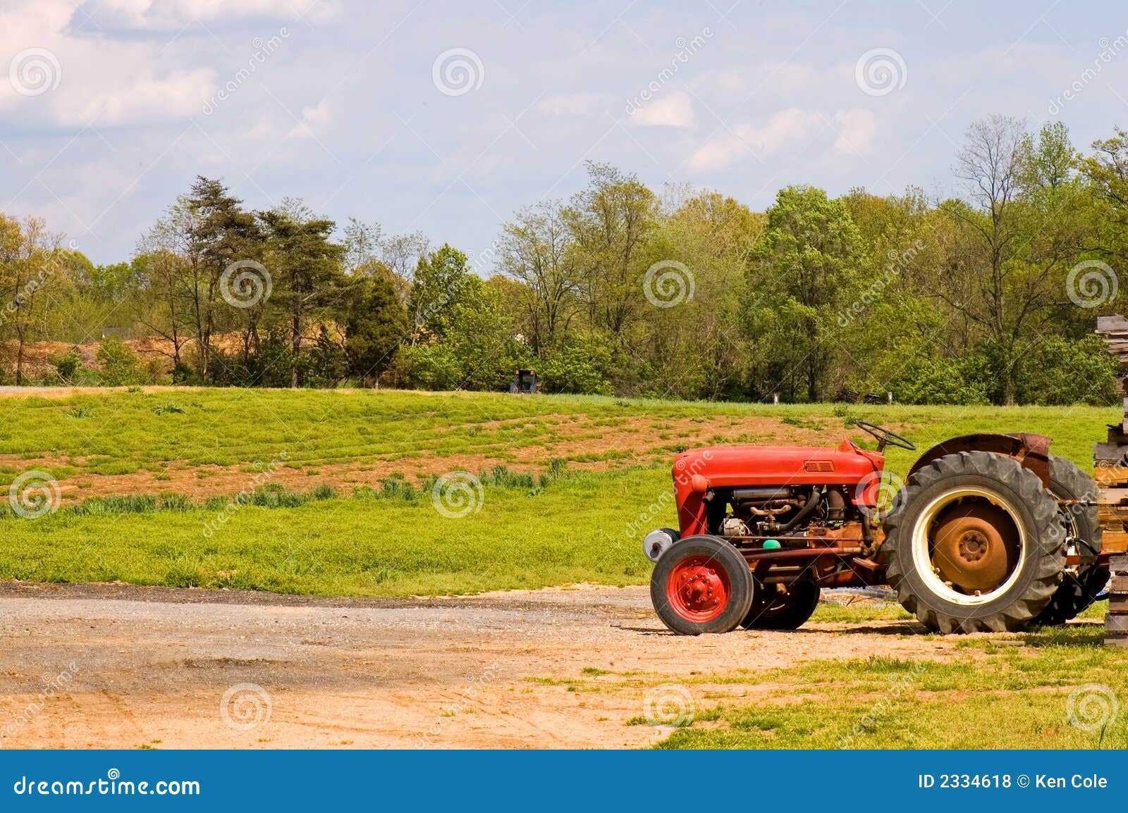 Trator de exploração agrícola vermelho perto do campo. Uma vista de um trator de exploração agrícola vermelho na borda de um campo na mola adiantada.