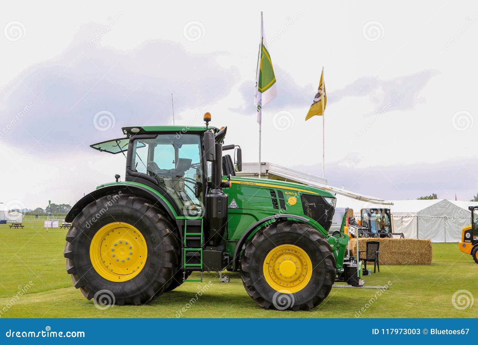 Trattore moderno di John Deere parcheggiato ad una manifestazione. Trattore moderno di 6250r John Deere parcheggiato ad una manifestazione con il supporto e le bandiere commerciali