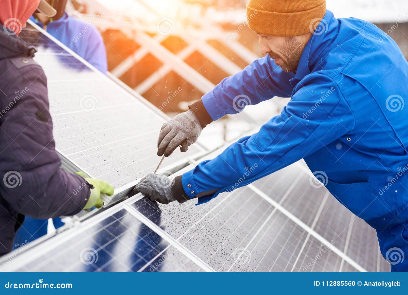 Travailleur avec des outils maintenant les panneaux photovoltaïques en hiver Ingénieurs installant les panneaux solaires