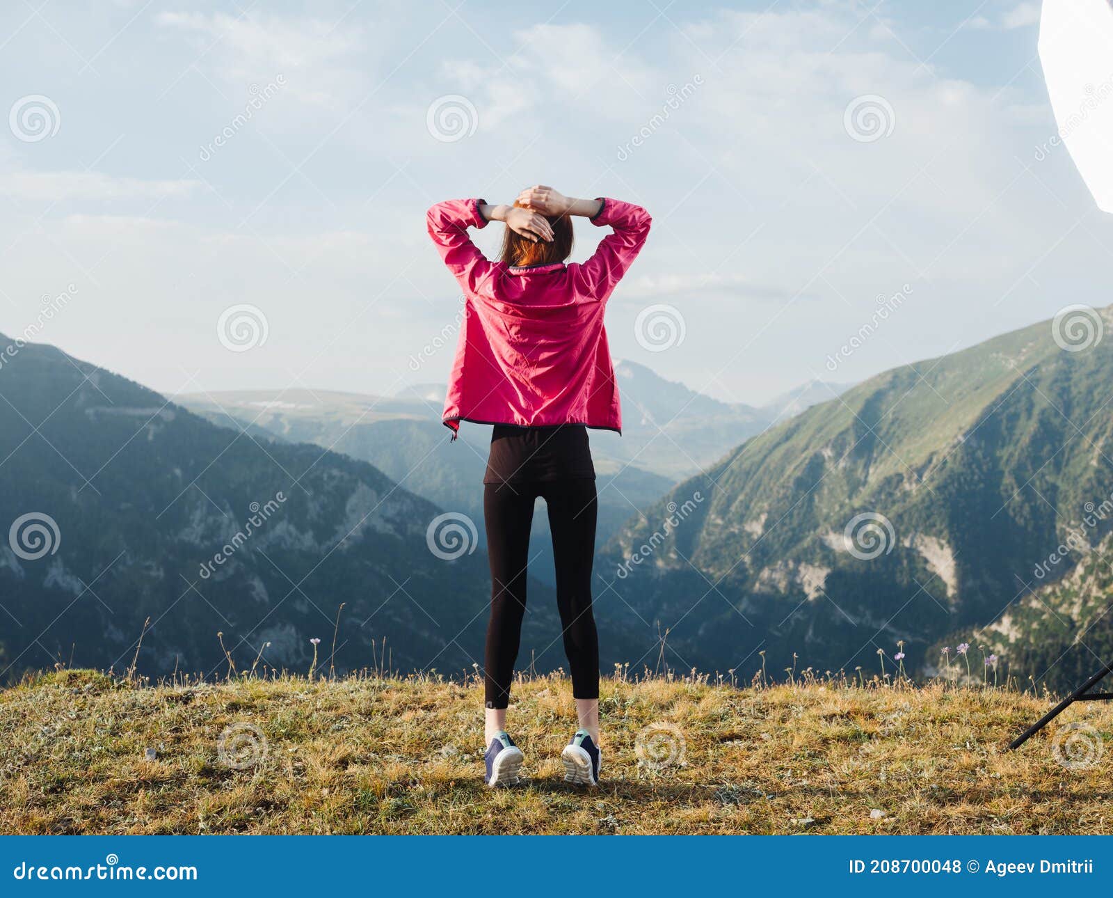 a traveler in leggings, sneakers and a jacket are resting in the mountains in nature