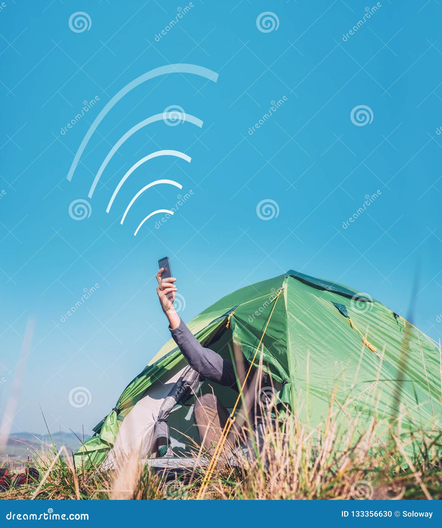 traveler sits in touristic camping tent and tries to catch cellular network. cell web coverage and roaming concept image.