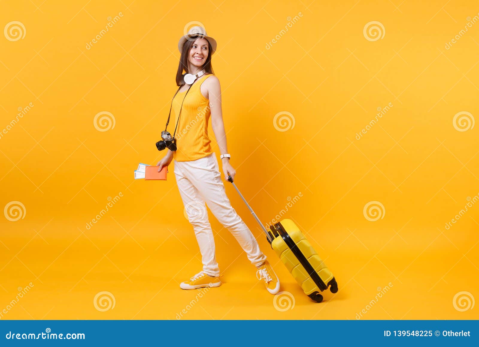 traveler tourist woman in summer casual clothes, hat with headphones on neck  on yellow orange background