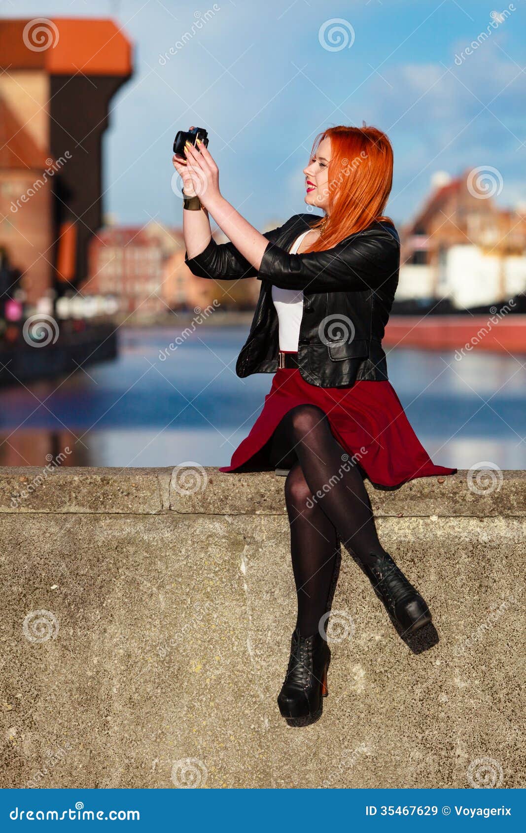 Traveler woman red hair girl with camera old town Gdansk. Female photographer taking pictures. Traveler woman red haired fashion girl with camera outdoors in european city, old town Gdansk river Motlawa in the background, Poland Europe