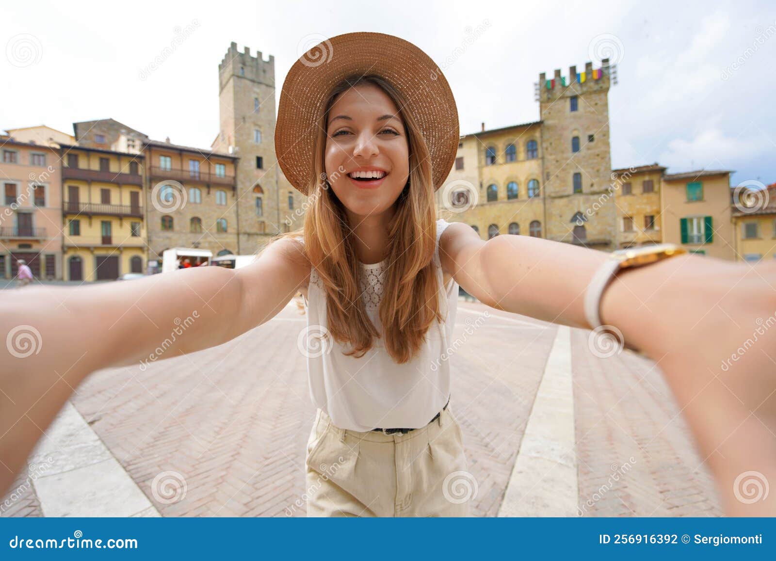 traveling in tuscany. smiling tourist girl in piazza grande square in the historic town of arezzo, tuscany, italy