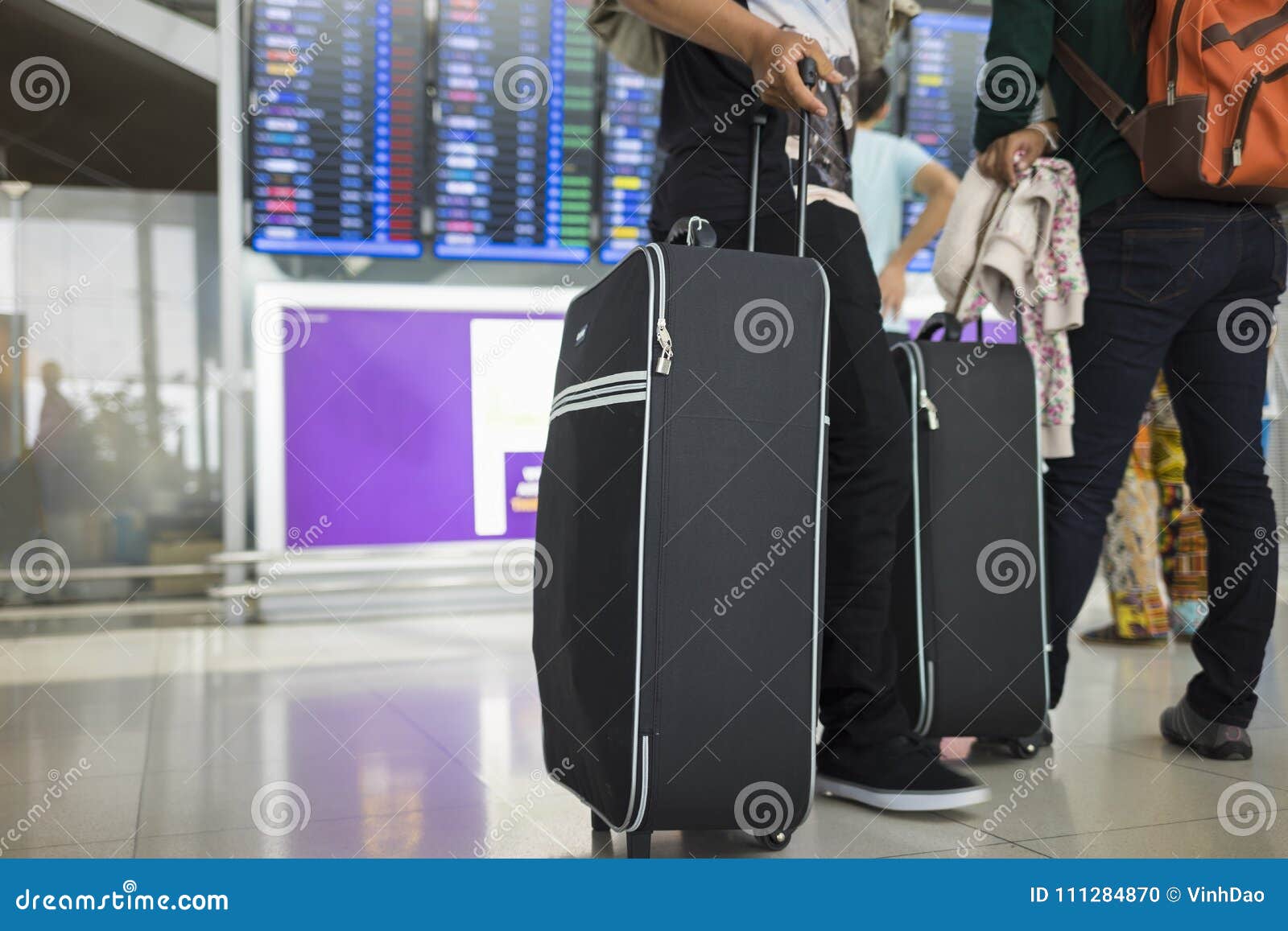 travelling suitcase against flight information board on background. concept of travel by airplane