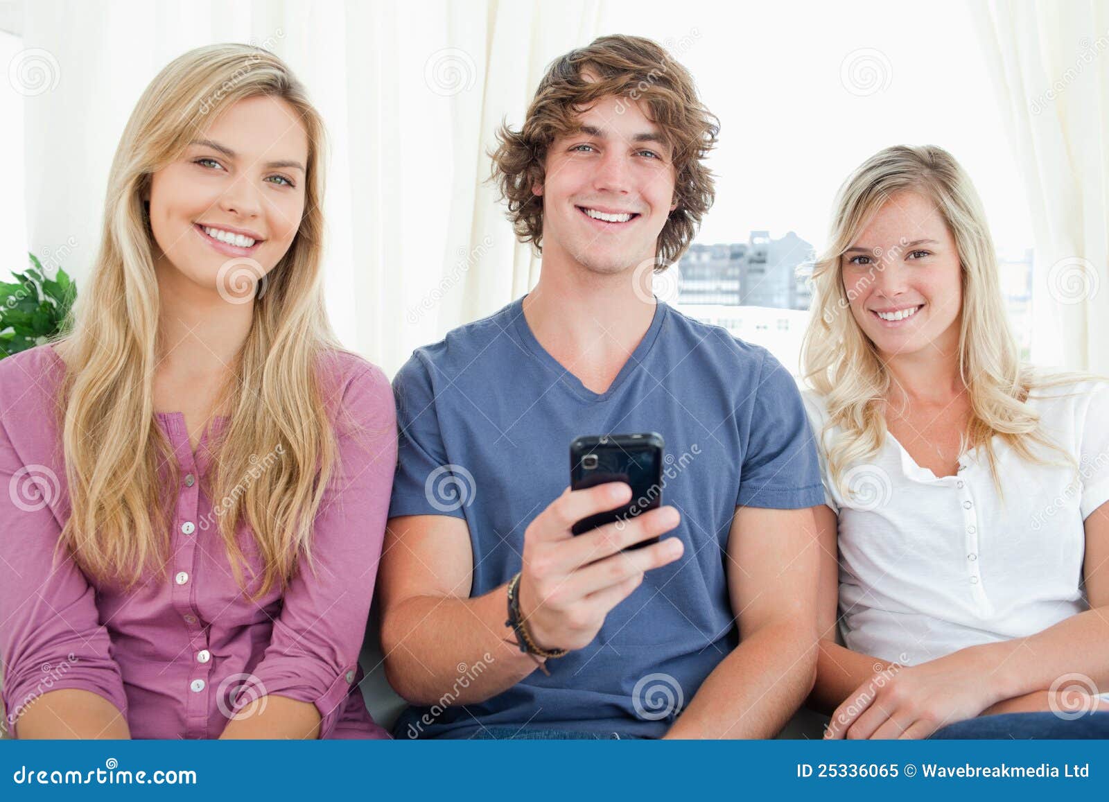 Tre amici che esaminano la macchina fotografica come il ragazzo ha un telefono in sua mano