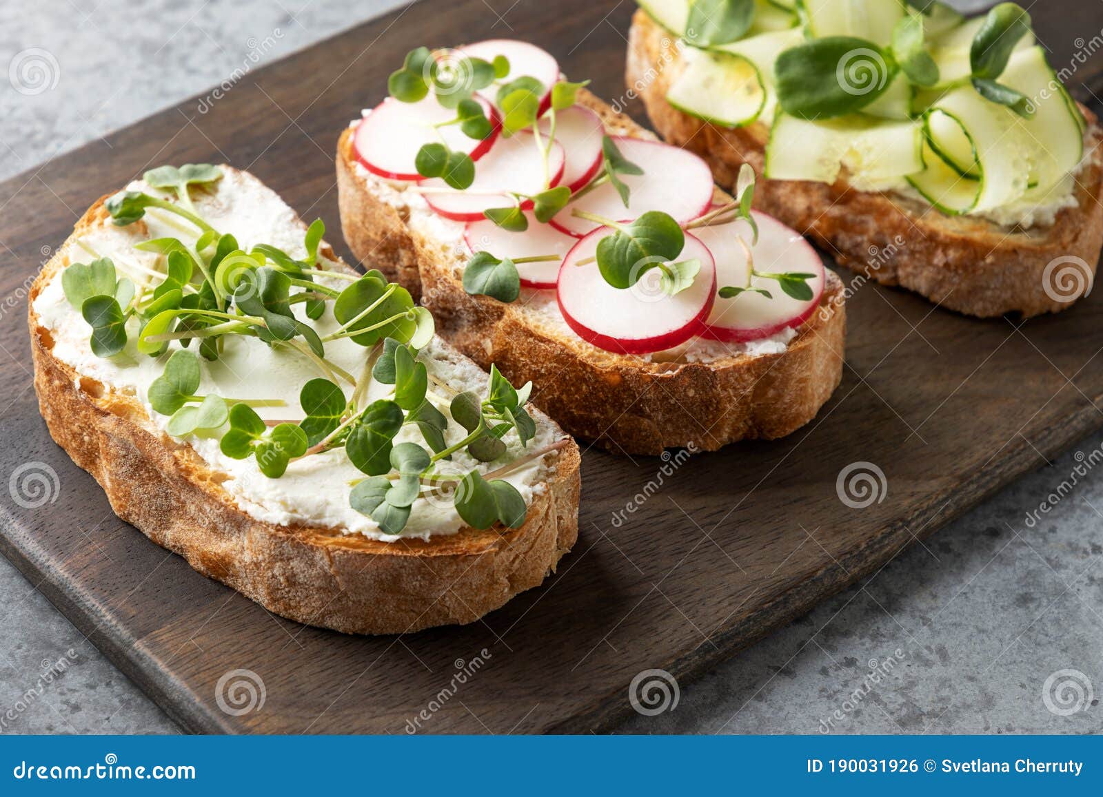tree sandwiches with fresh radish microgreens and cream cheese on grey background. close up
