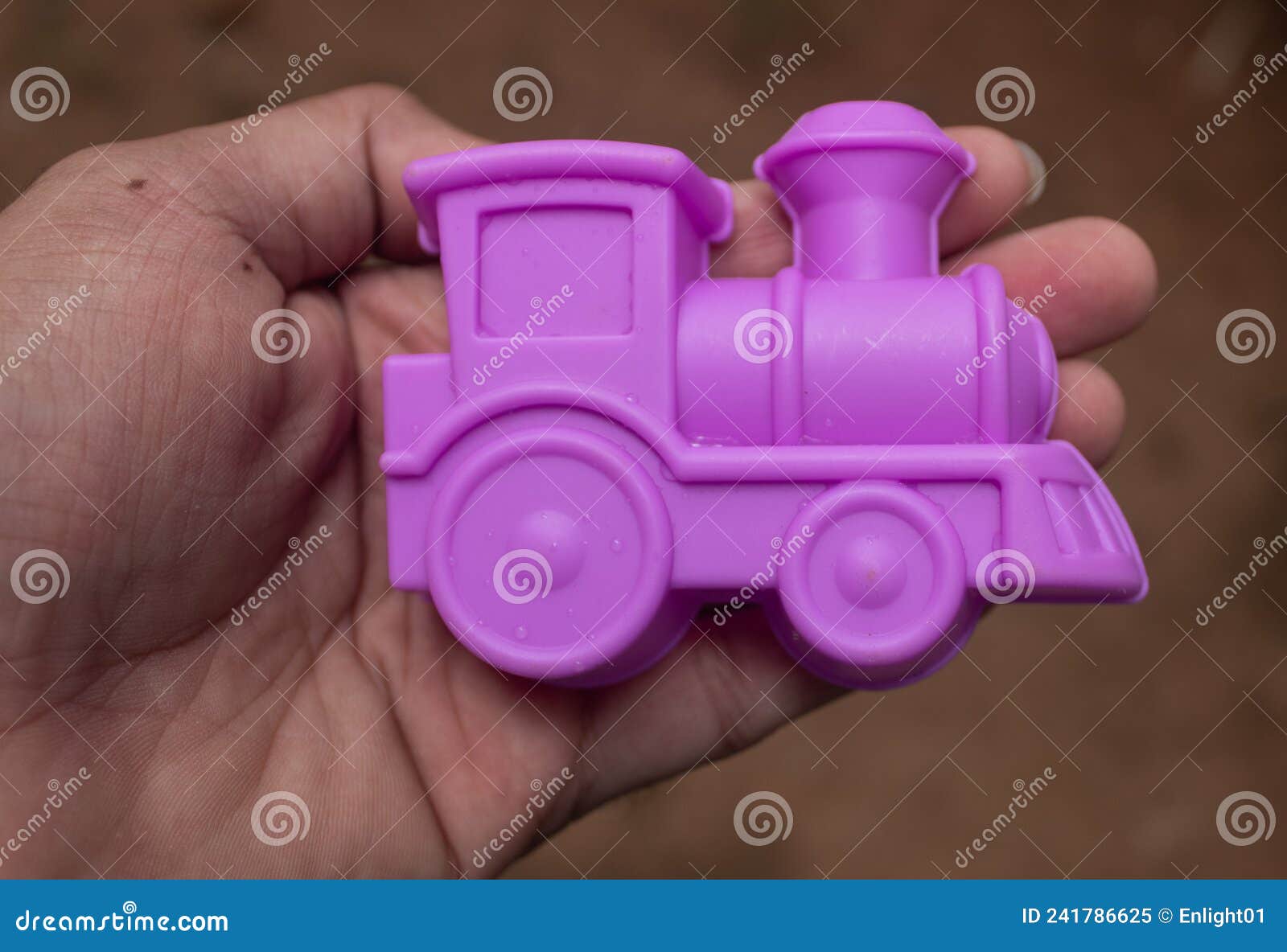 Trem de brinquedo roxo. Tiro certeiro de um comboio de brinquedo roxo mantido à mão