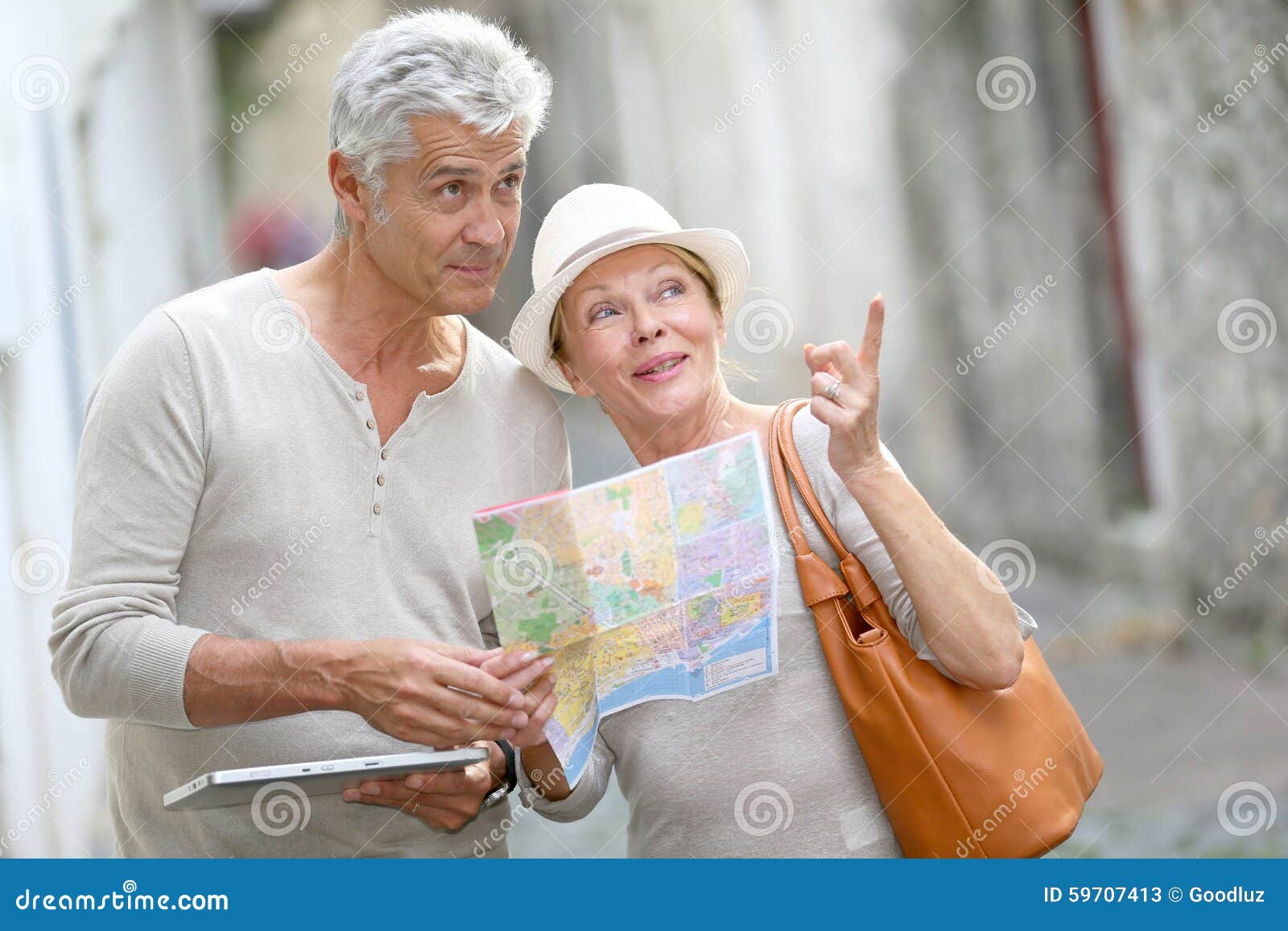 trendy senior tourists visiting town using tablet and map