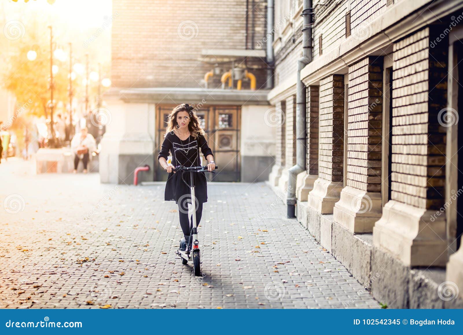 trendy woman, beautiful brunette girl riding electric scooter in city