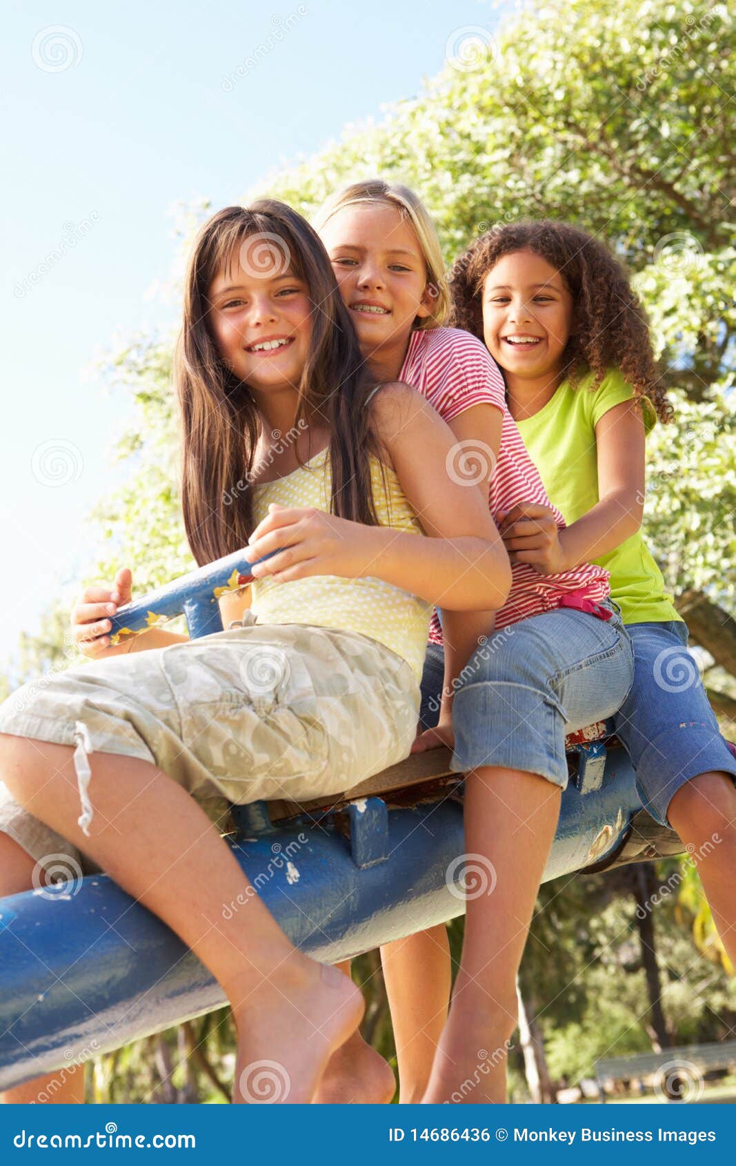 Tres muchachas que montan en el balancín en patio. Tres muchachas que montan en el balancín en el patio que sonríe en la cámara