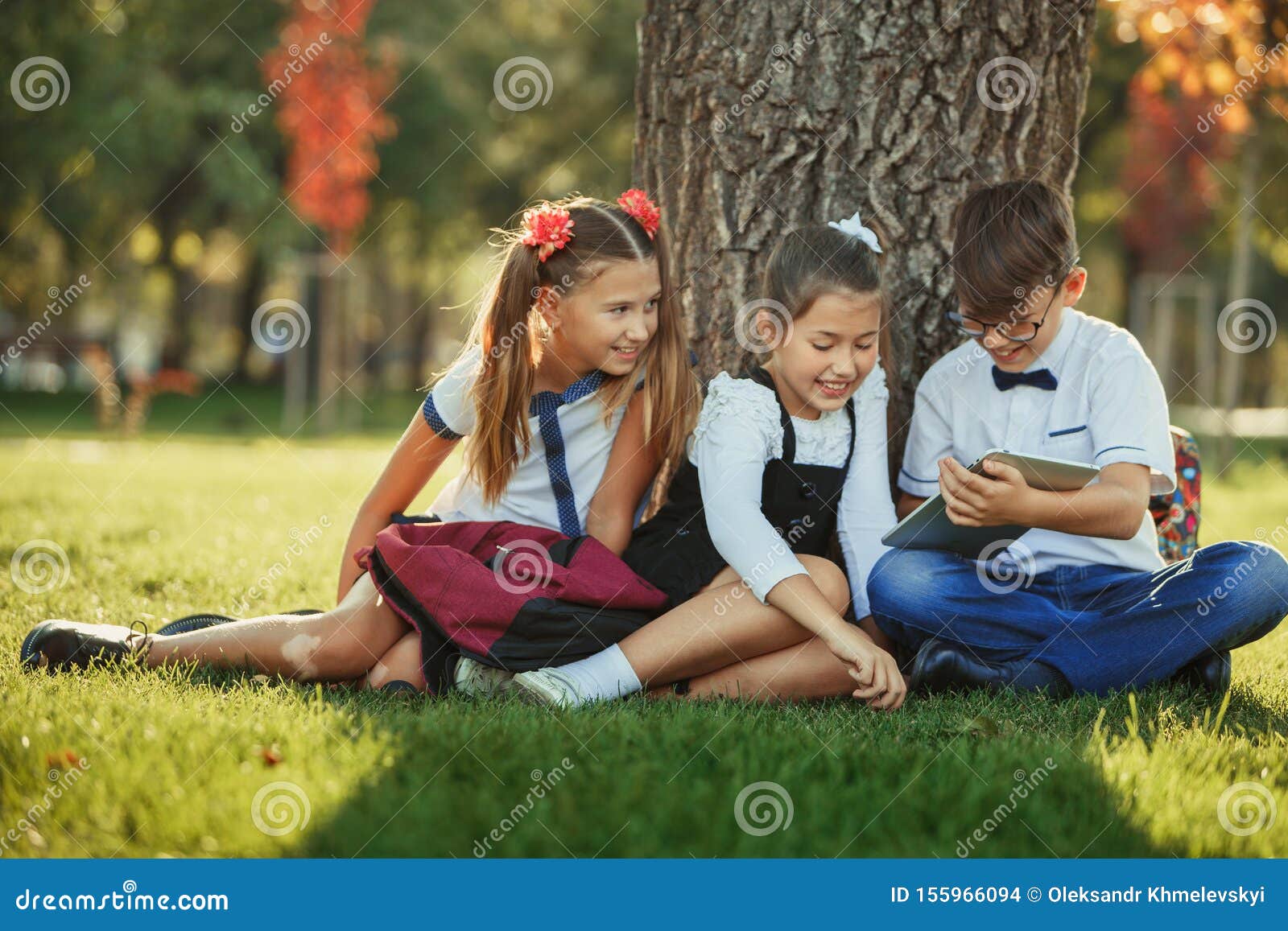 Tres Sonrientes Amigos De La Escuela Sentados En El Parque Sobre El