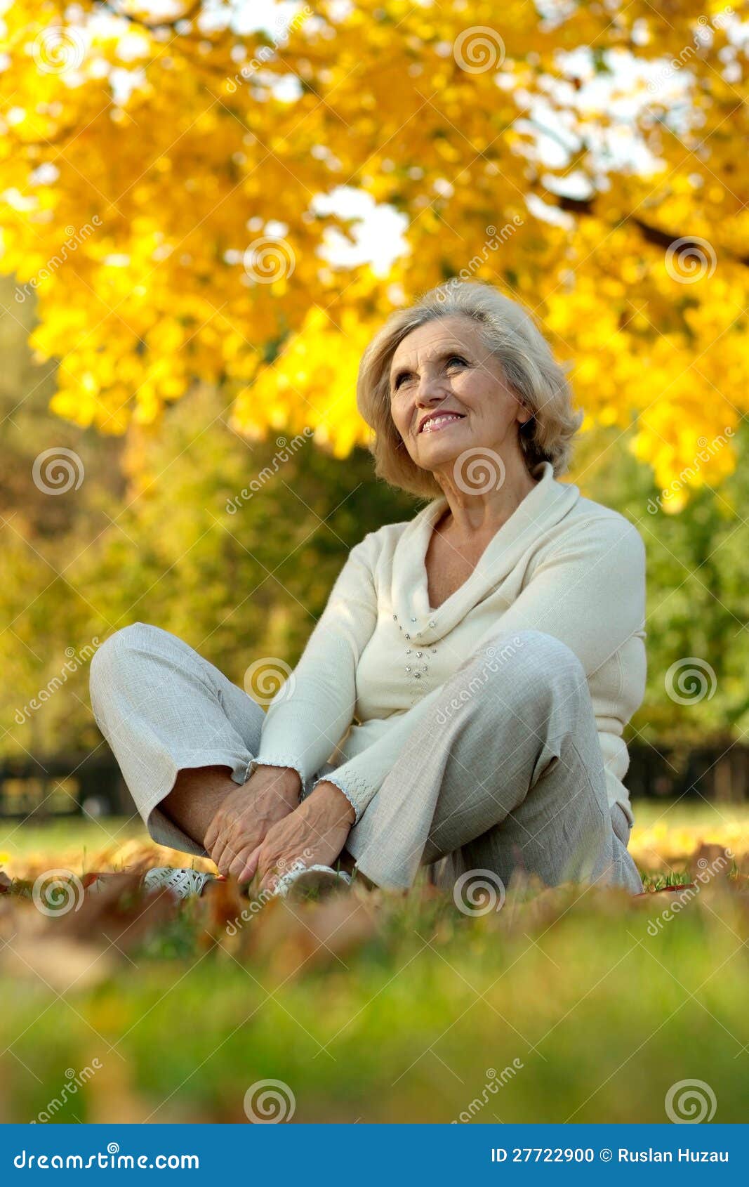 Stående av en trevlig gammal kvinna som sitter i höstparken