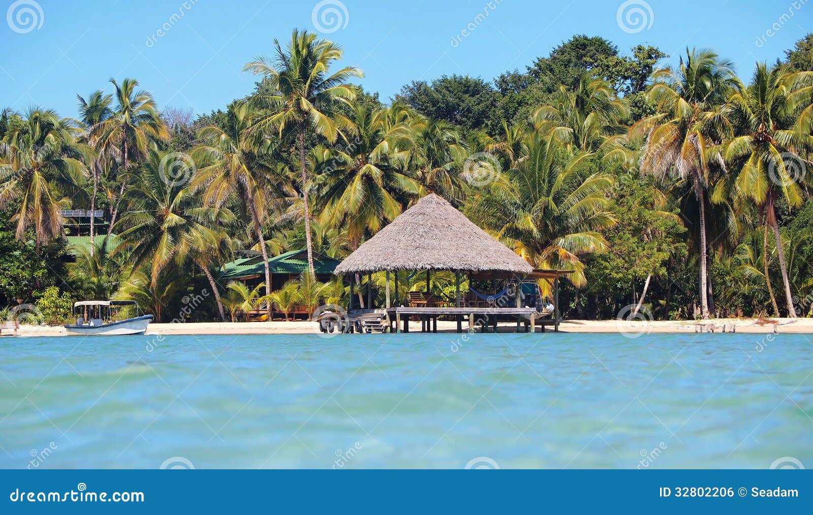 Tropiskt strandhemparadis med palapa över vattnet