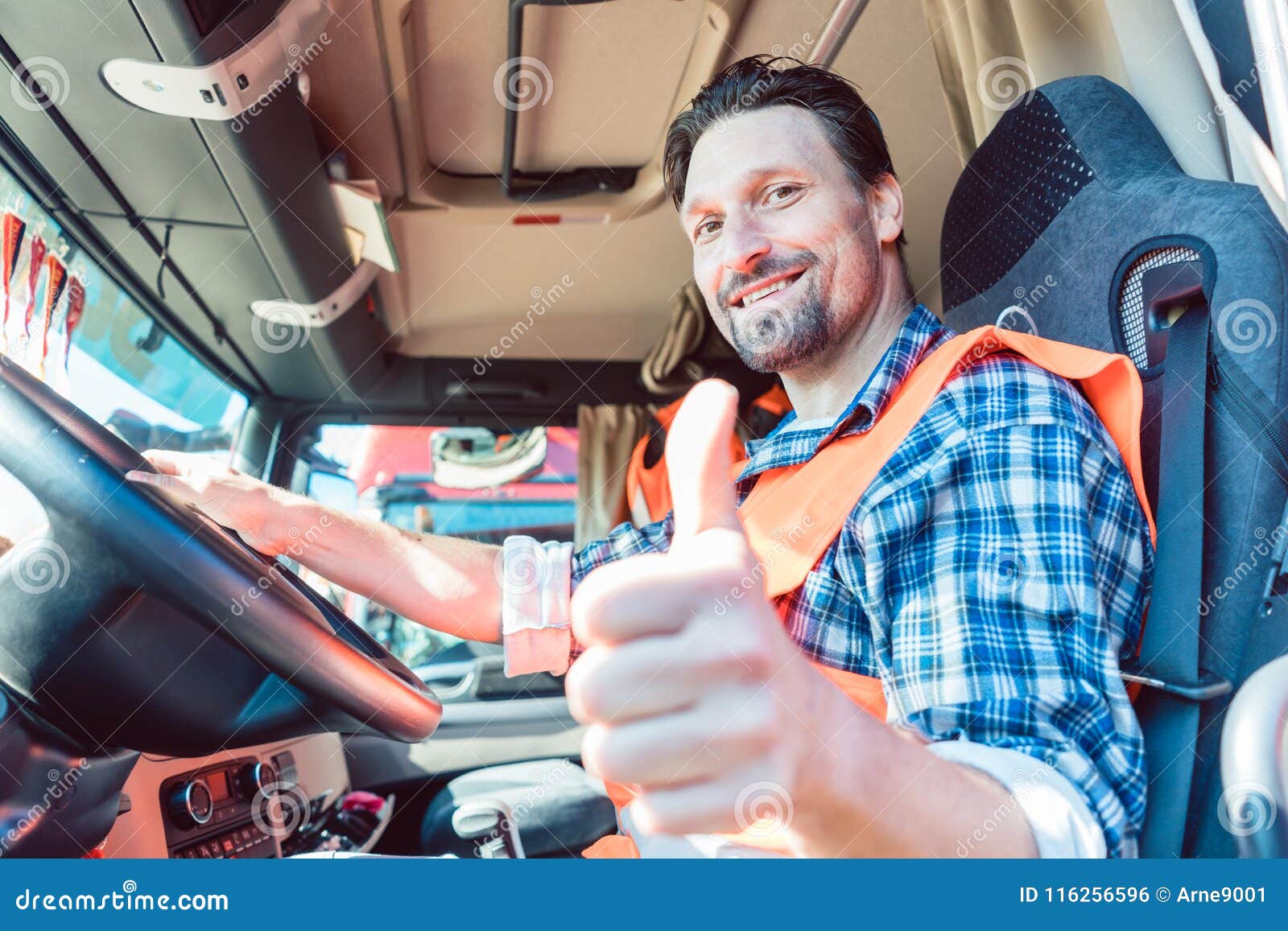 truck driver sitting in cabin giving thumbs-up