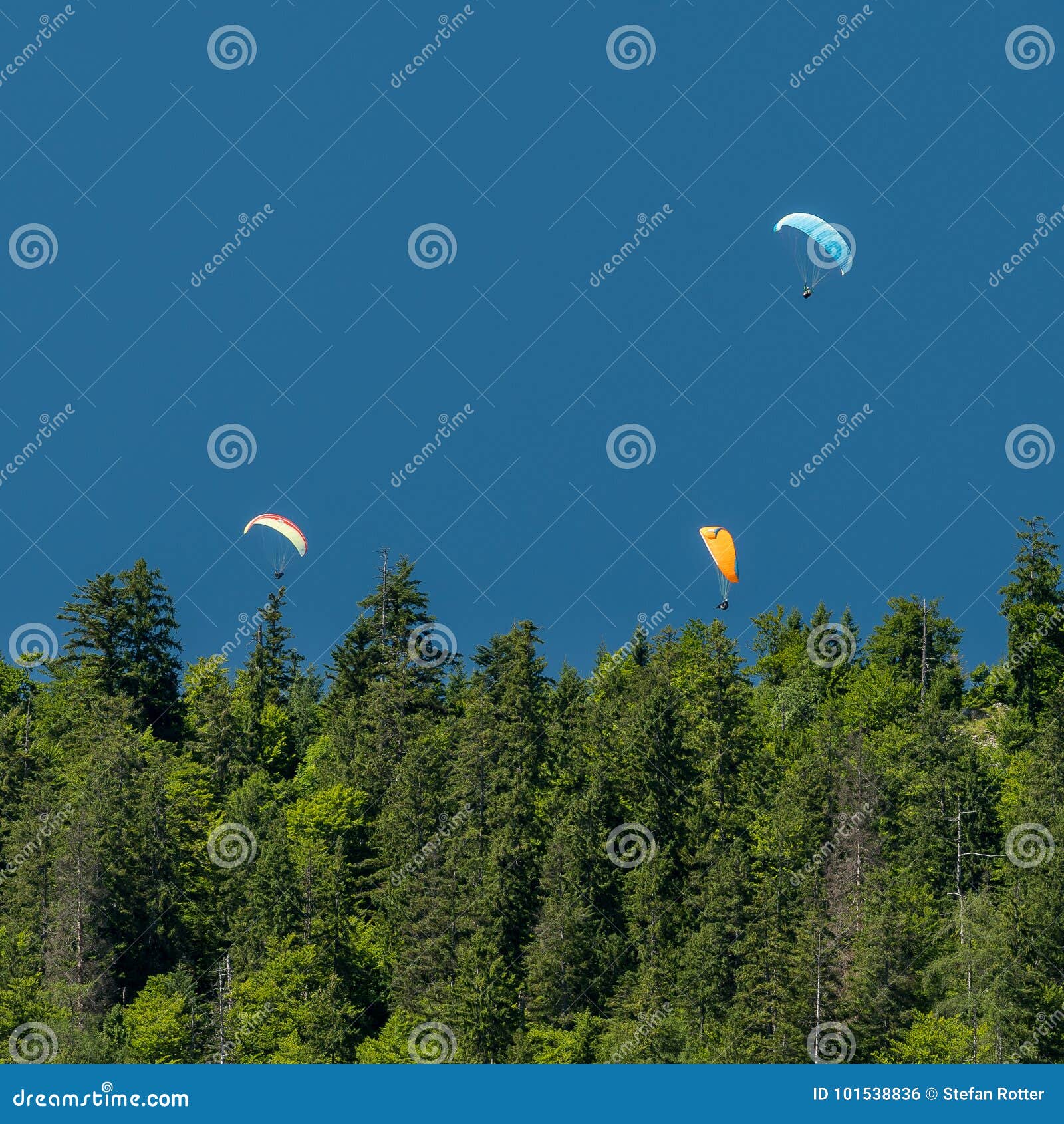 Três paragliders no céu azul das montanhas. Três paragliders nas montanhas acima de um céu azul da floresta