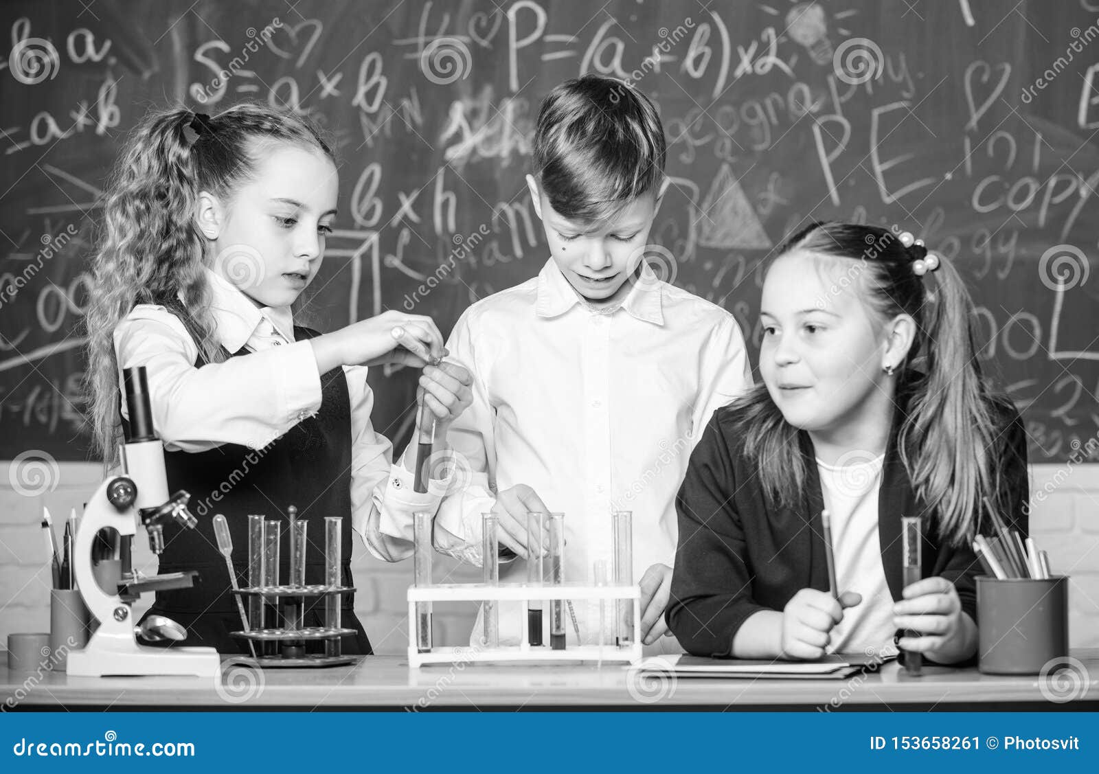 Test tubes with substances. Formal education. Girls and boy student conduct school experiment with liquids. School laboratory. Group school pupils study chemical liquids. School chemistry lesson.