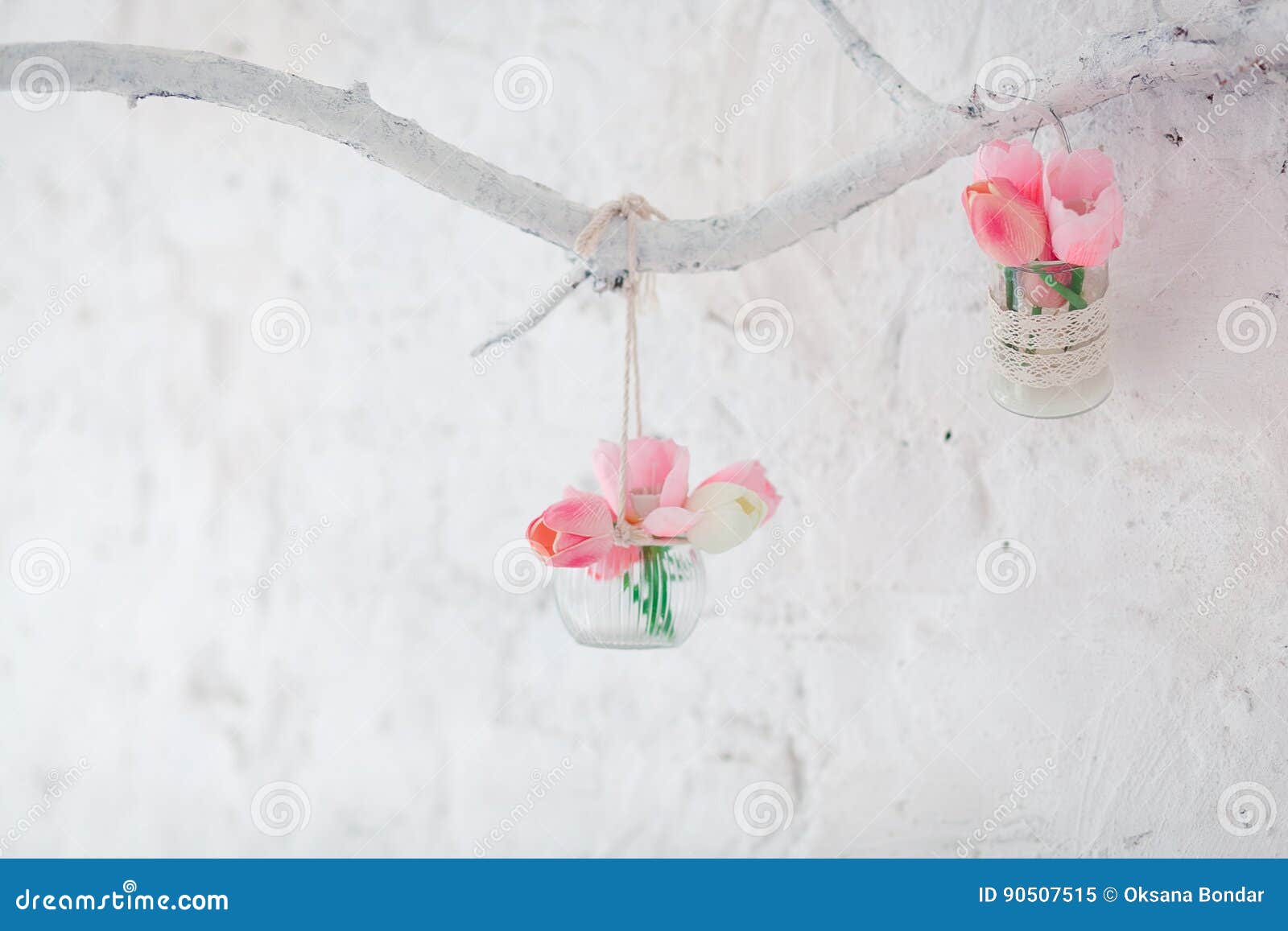 Tulips in Vases Hang on a Decorative Branch on a Wall with White Bricks