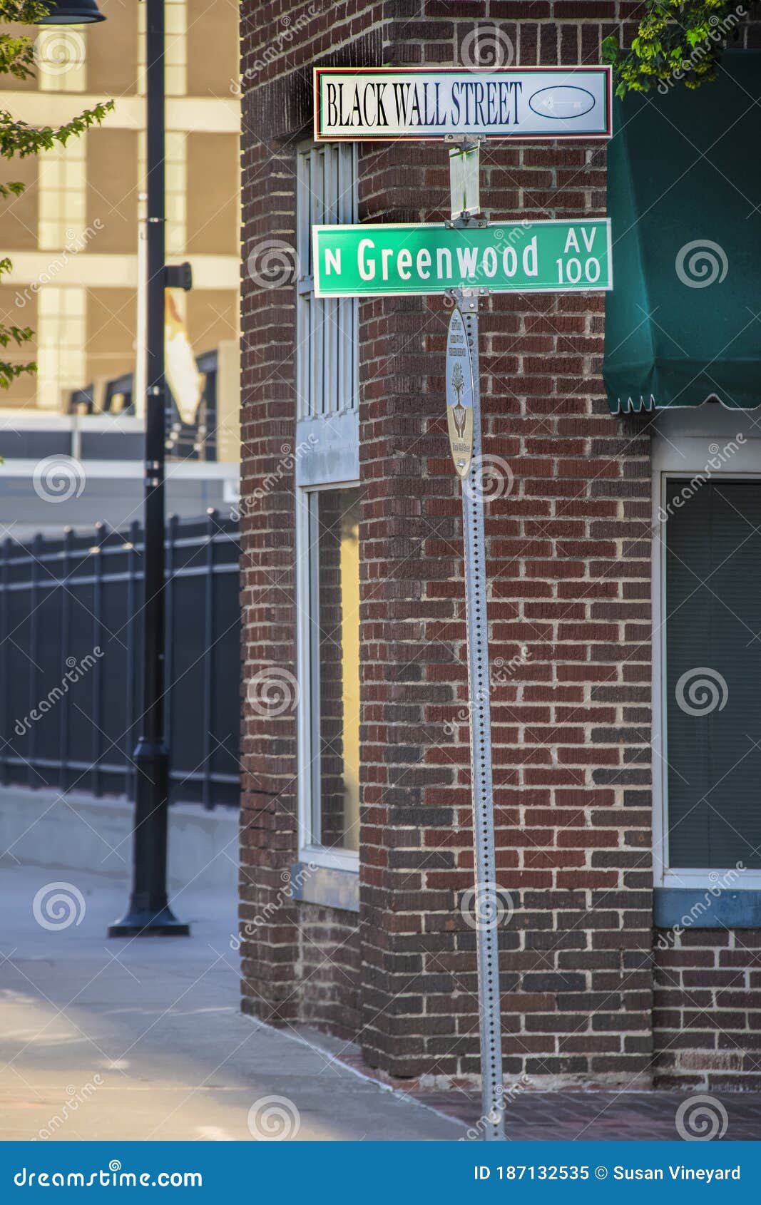 tulsa usa street sign that reads black wall street and greenwood av against brick building-site of historic tulsa race
