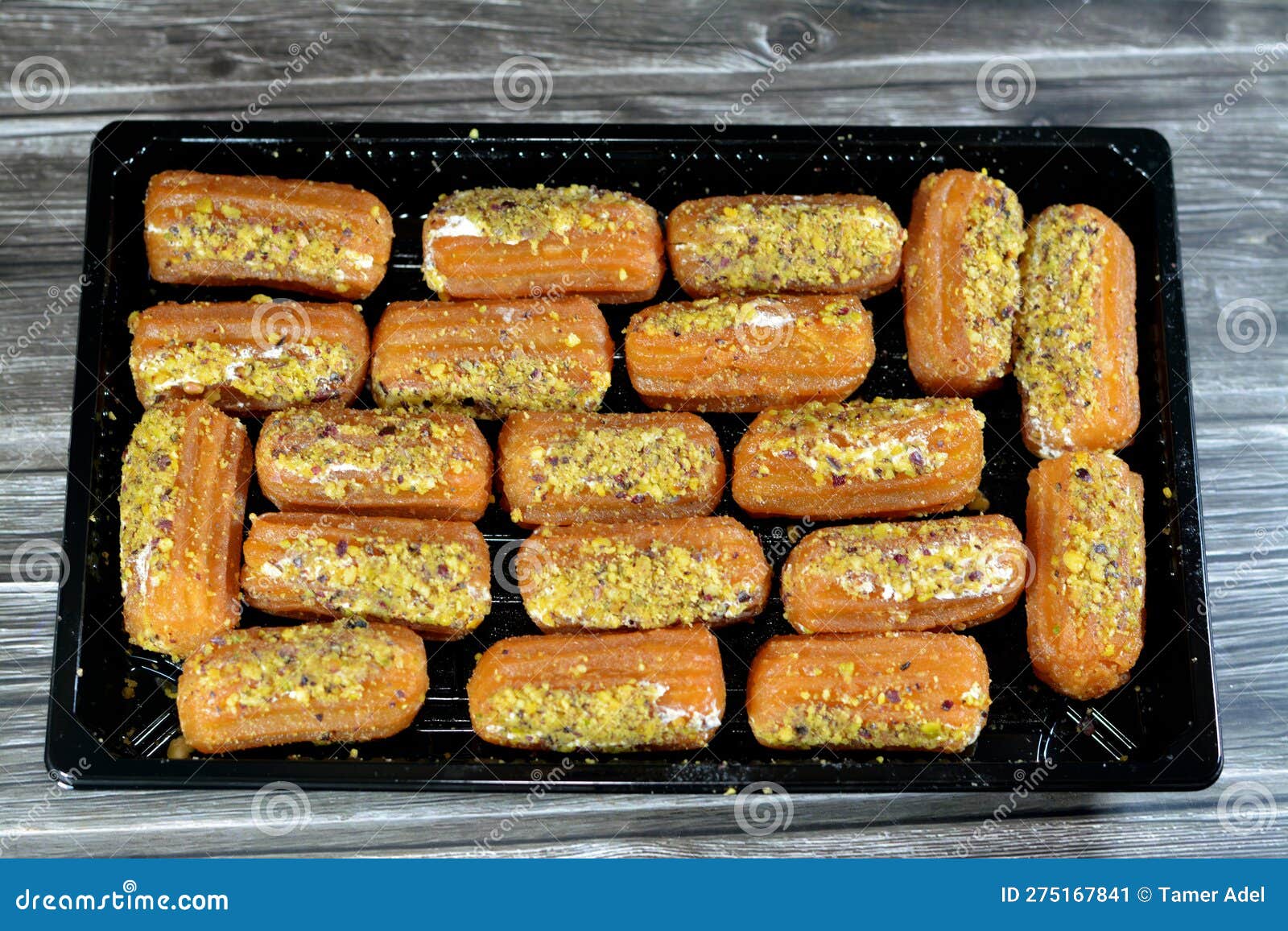 tulumba, bamiyeh or balah el sham stuffued with whipped cream and covered with pistachios and nuts, deep fried batter dessert