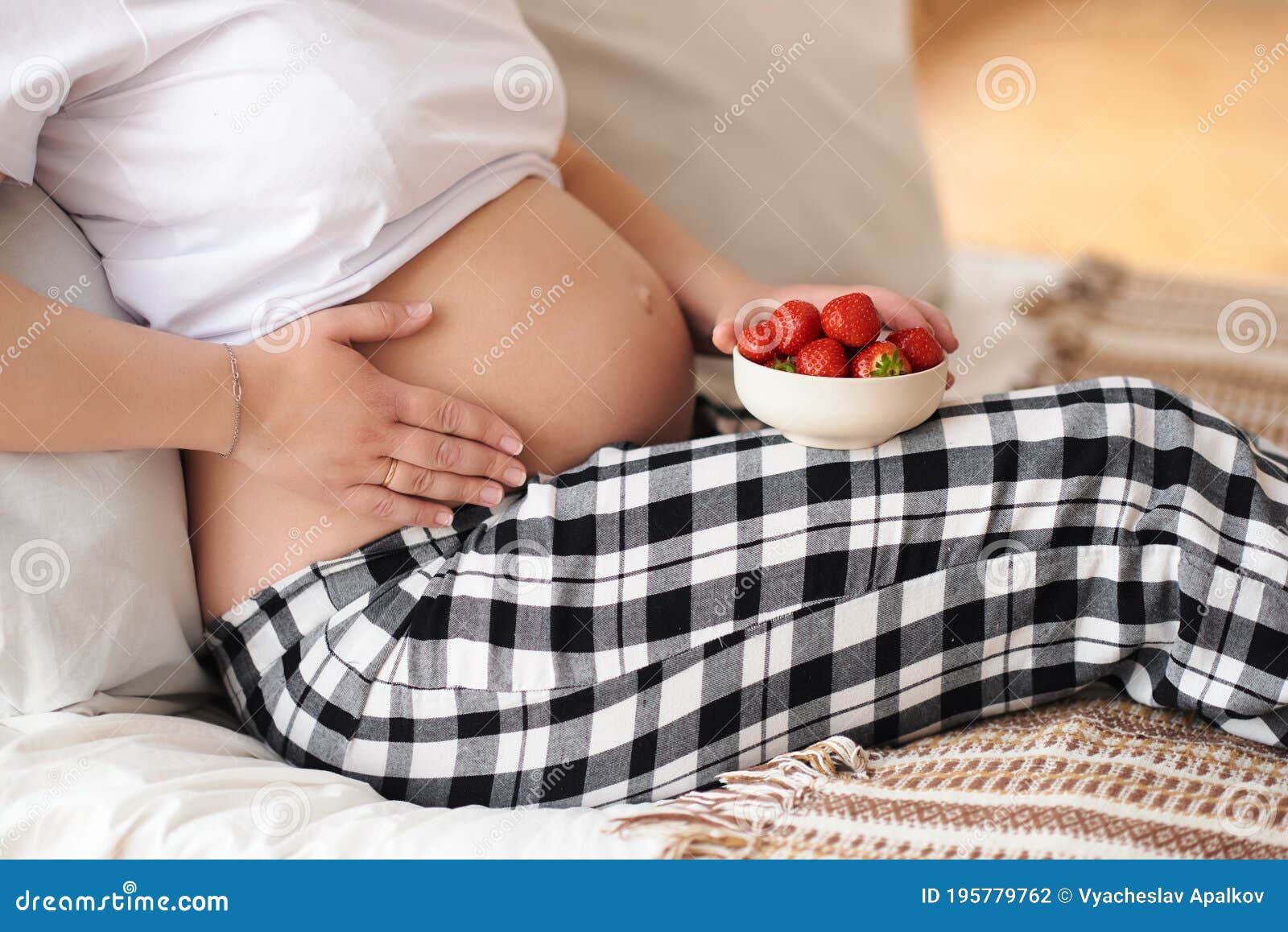 tummy of a pregnant woman and strawberries