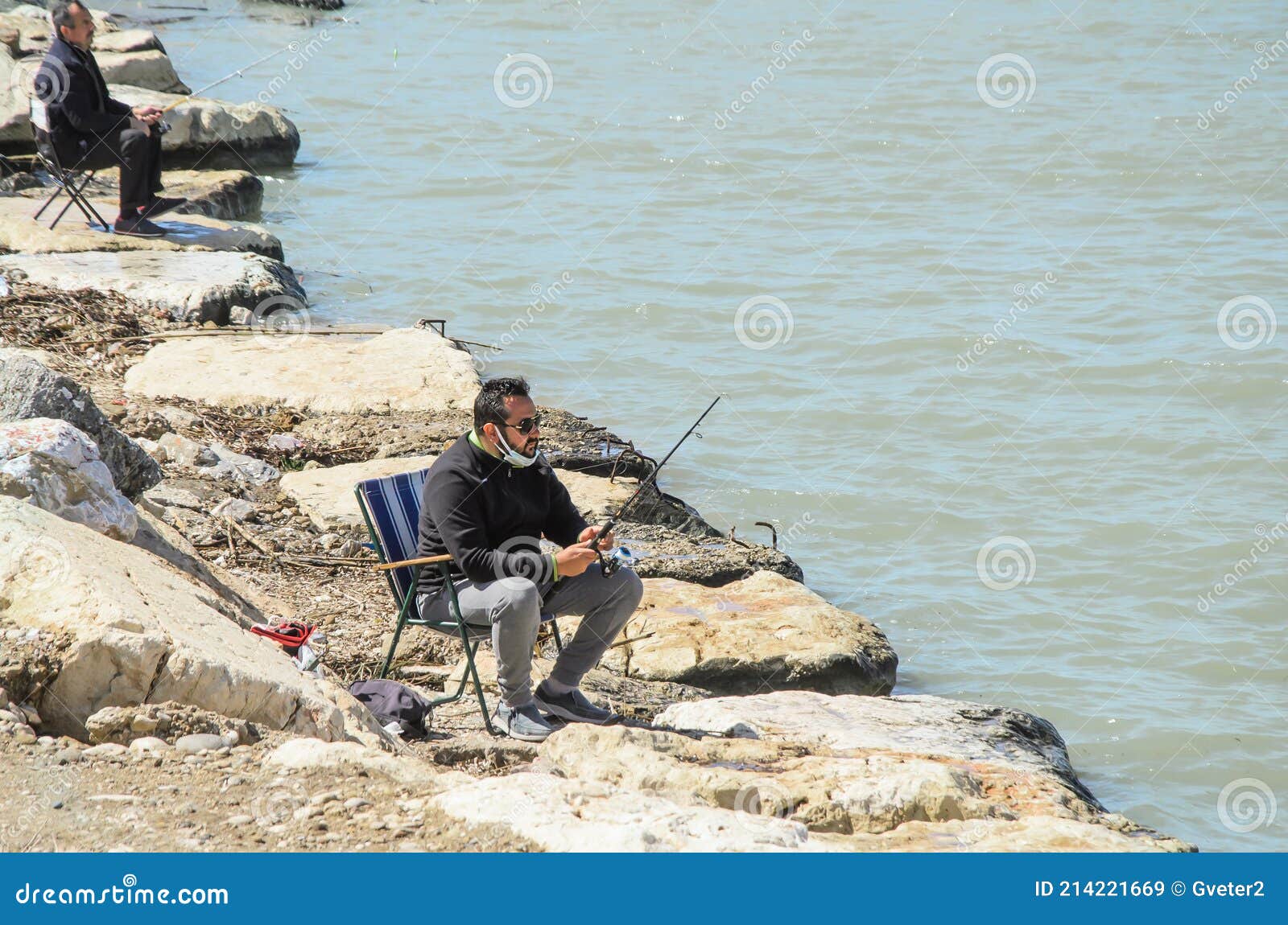 Turkish Man Fishermen Sitting on a Small Folding Chair on Stone