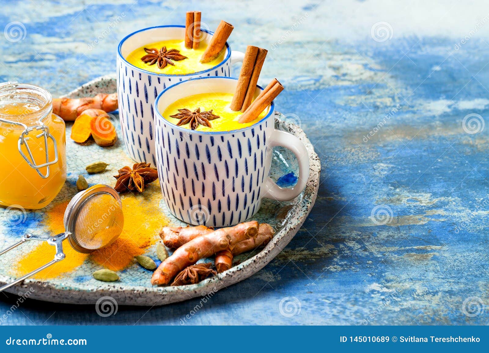 turmeric golden milk latte with cinnamon sticks and honey. detox, immune boosting, anti inflammatory healthy cozy drink.