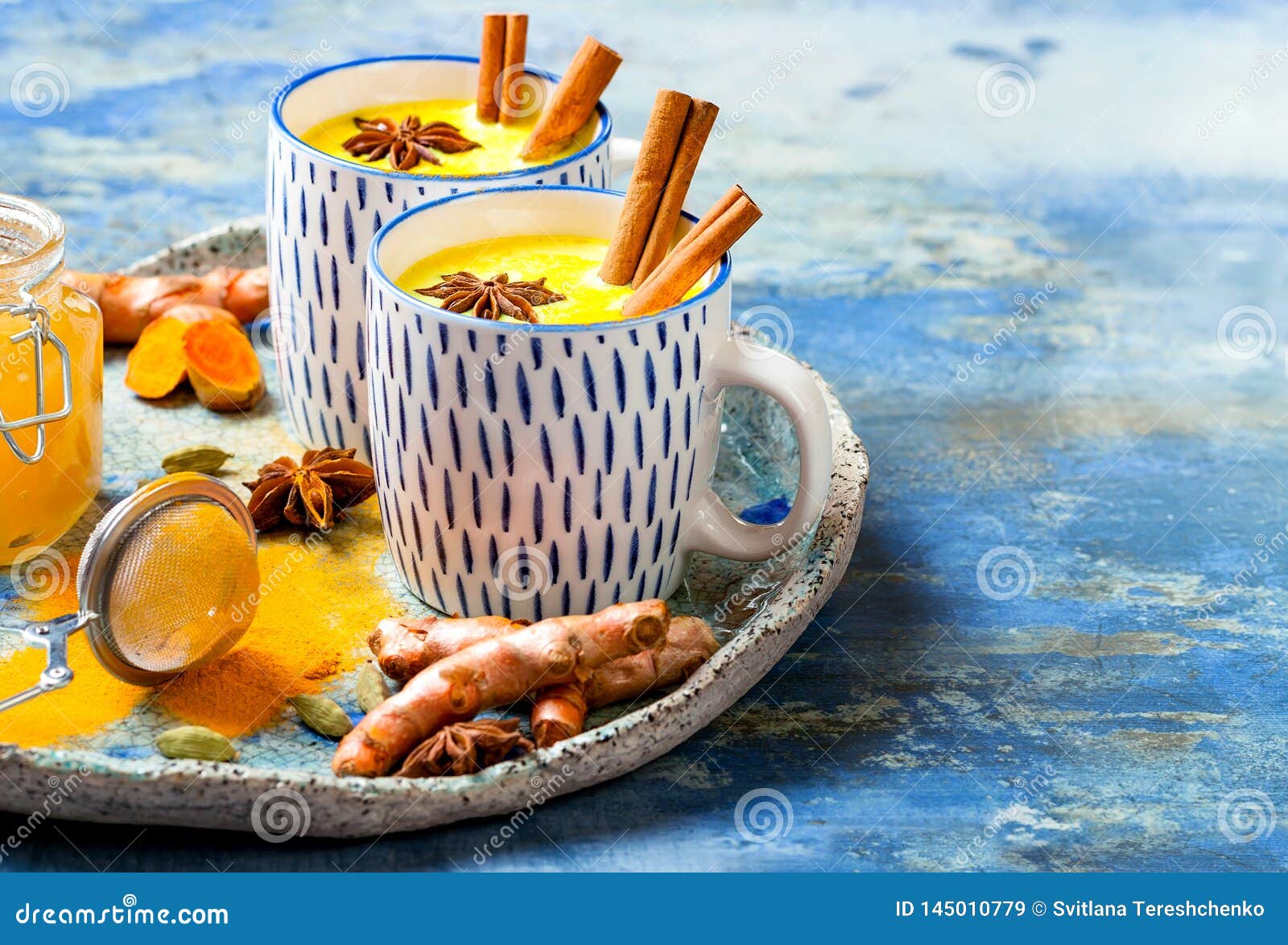 turmeric golden milk latte with cinnamon sticks and honey. detox, immune boosting, anti inflammatory healthy cozy drink.