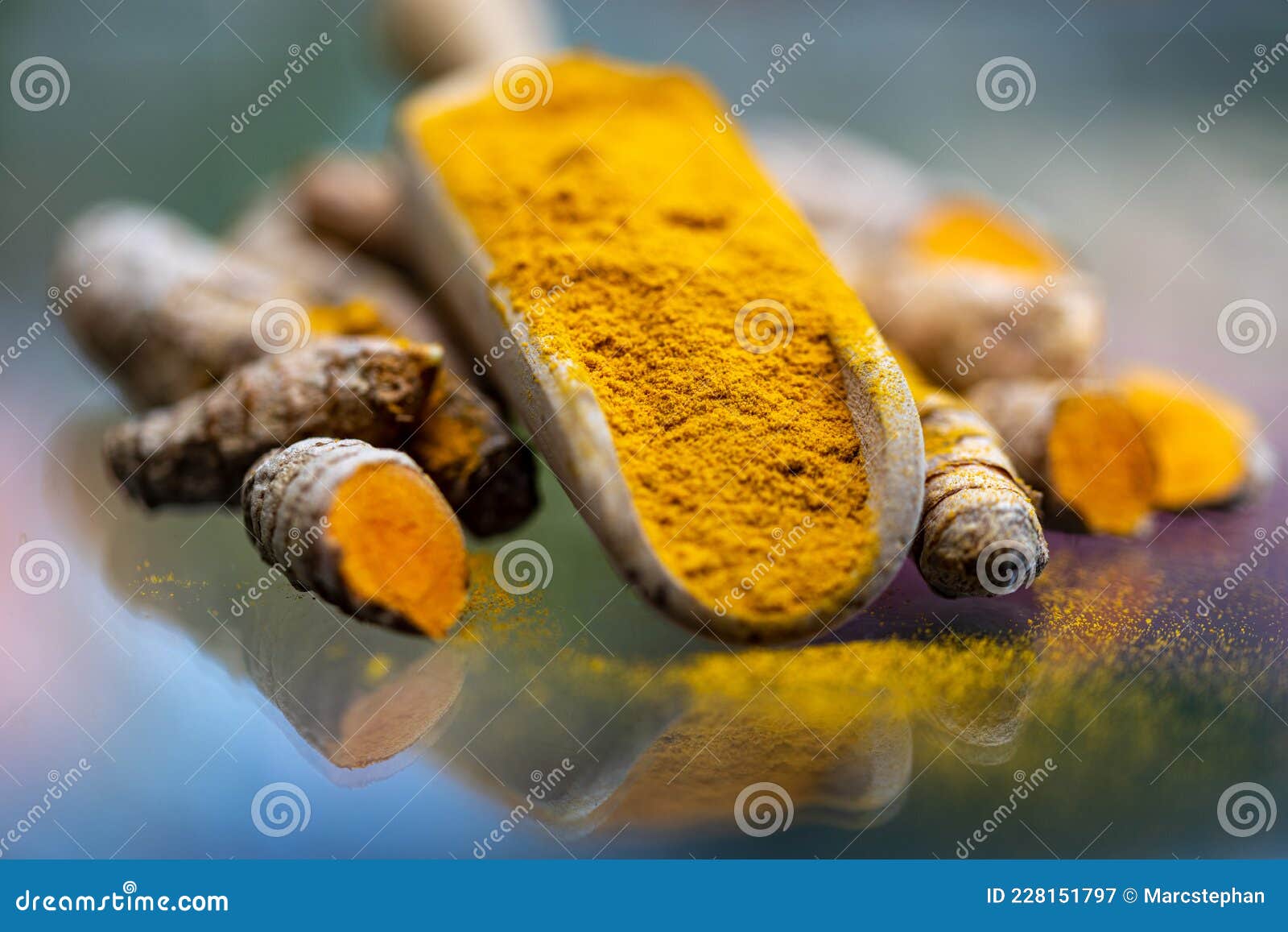 turmeric powder (kurkuma) in a wooden spoon and roots