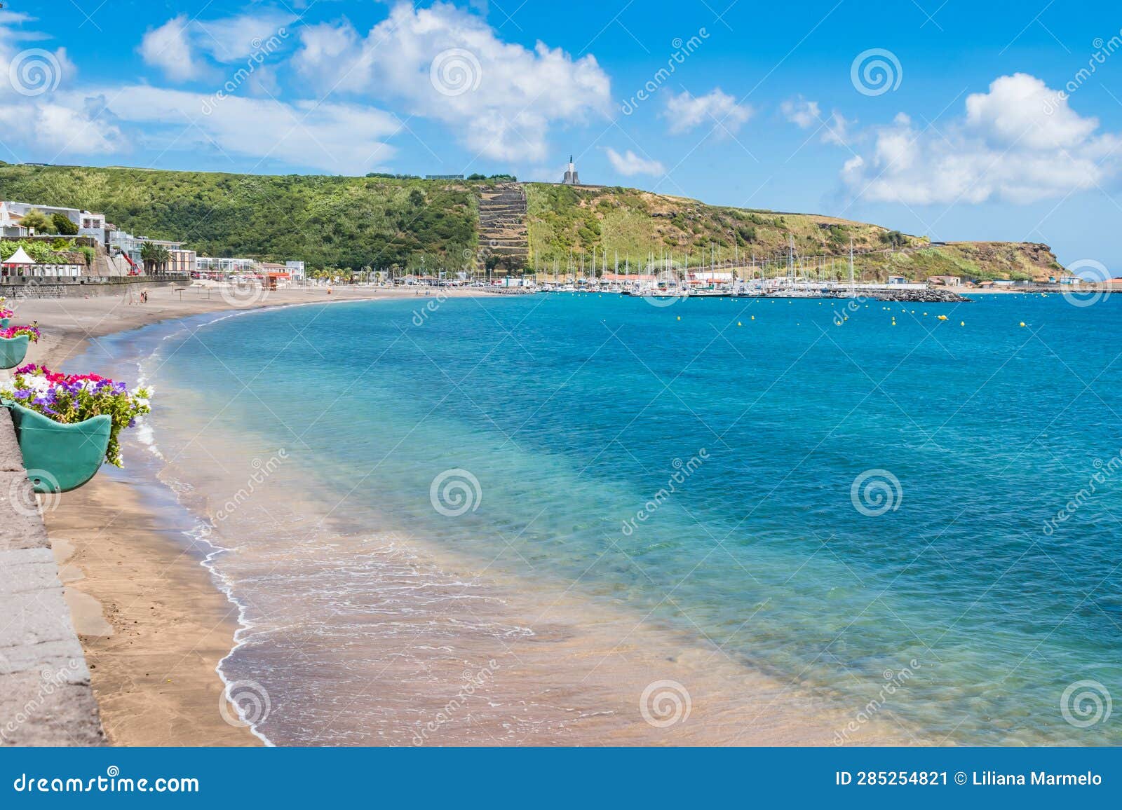 turquoise water of the bay of praia da vitÃ³ria with hill with the facho viewpoint in porto martins, terceira - azores portugal