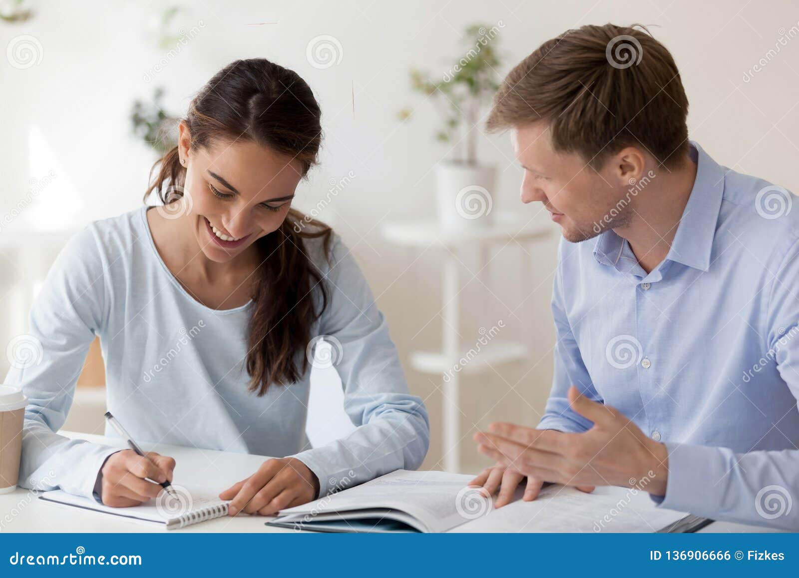 tutor helping female student making notes with research work