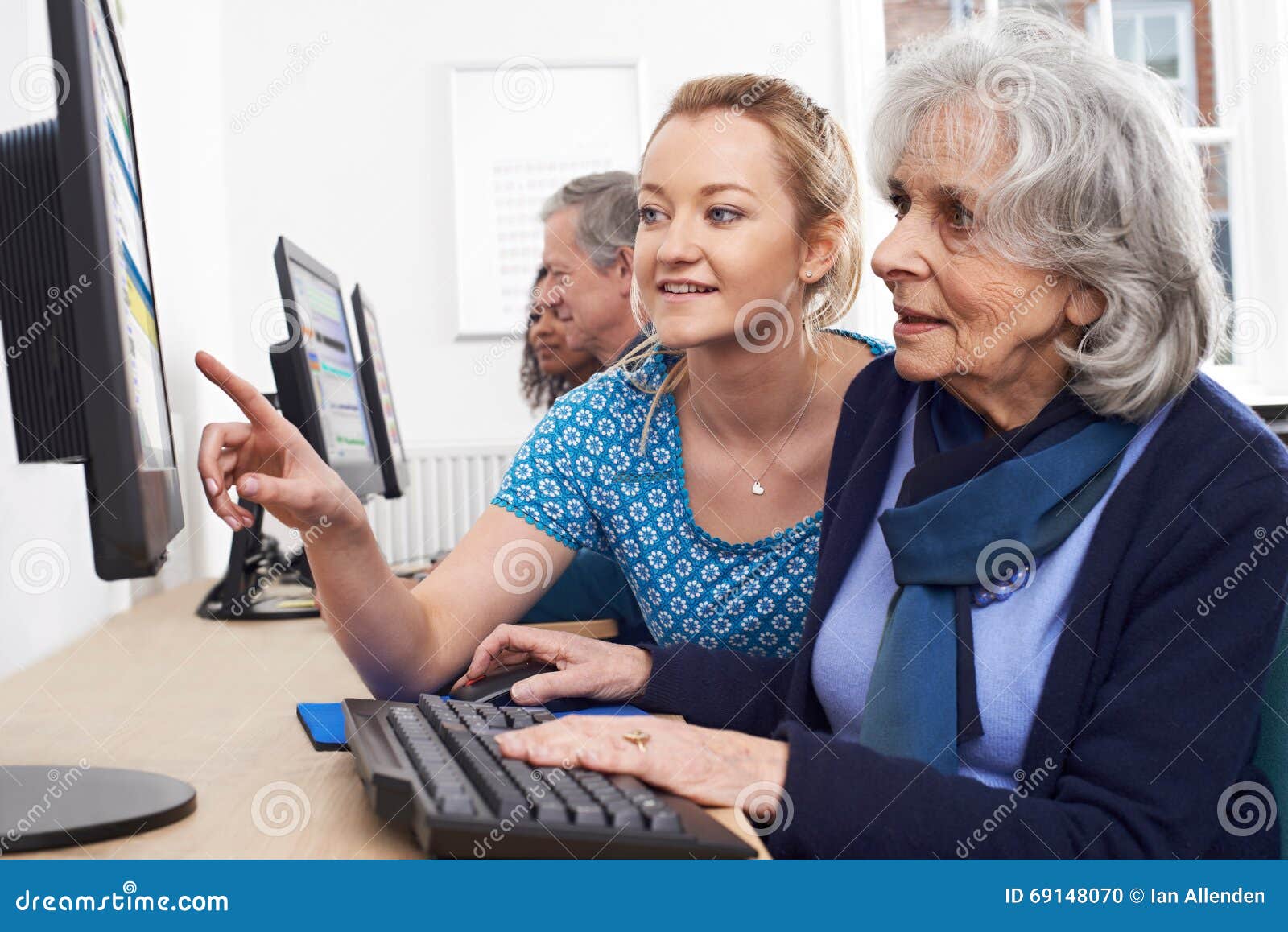 tutor helping senior woman in computer class