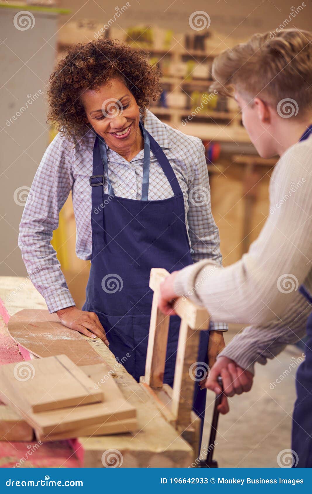 Tutor with Male Carpentry Student in Studying for College Apprenticeship Using Bench