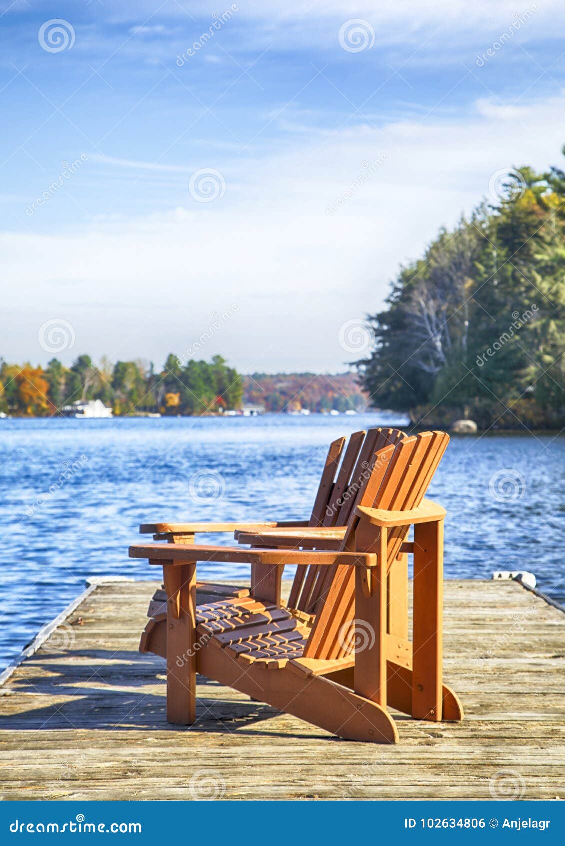 Twee Muskoka-stoelen op een houten dok bij een blauw de herfstmeer