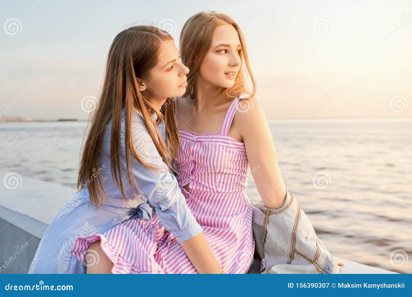 Twee Prachtige Dames Met Lange Adem Zitten Aan De Kust Stock Afbeelding