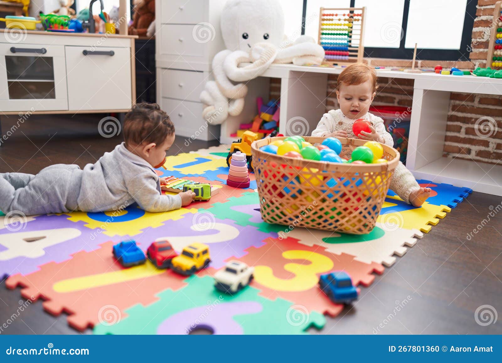 Two Adorable Babies Playing with Balls Sitting on Floor at Kindergarten