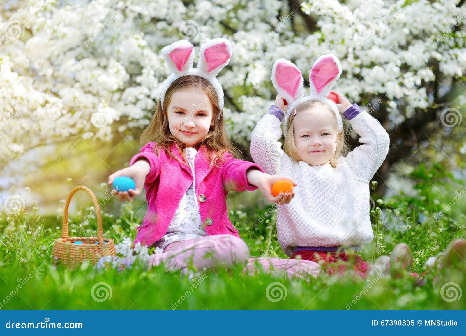 Two Adorable Little Sisters Hunting for Easter Egg in Blooming Spring