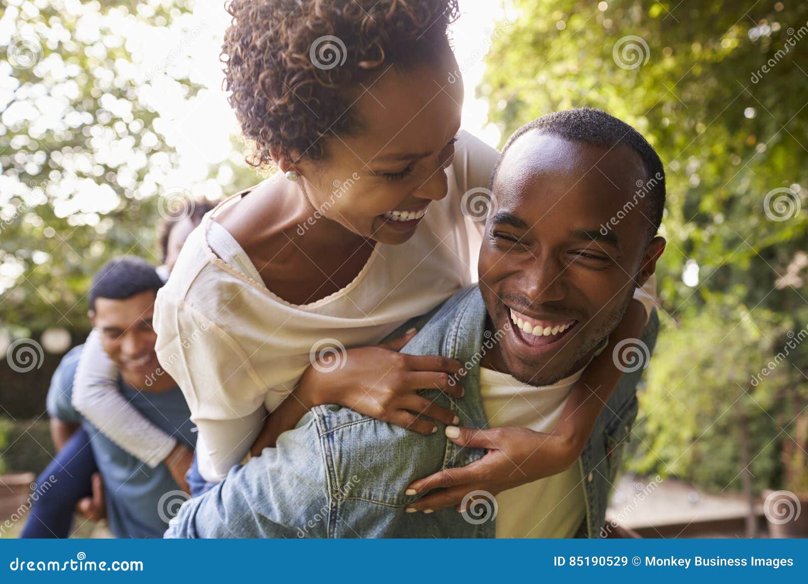 two adult black couples piggybacking looking at each other