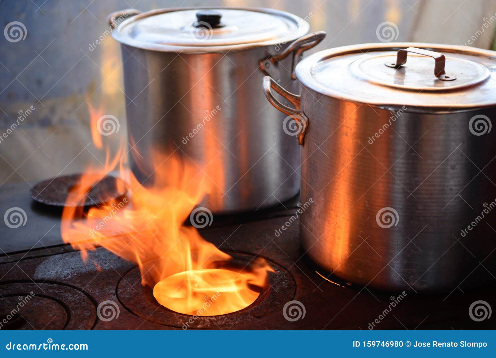 Two Aluminum Pans on Wood Stove with Fire Flame beside Stock Photo