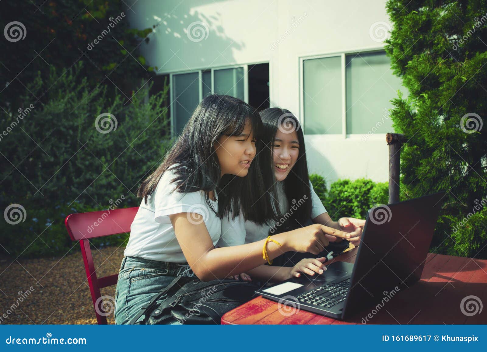 two asian teenager typing on computer labtop happiness emotion