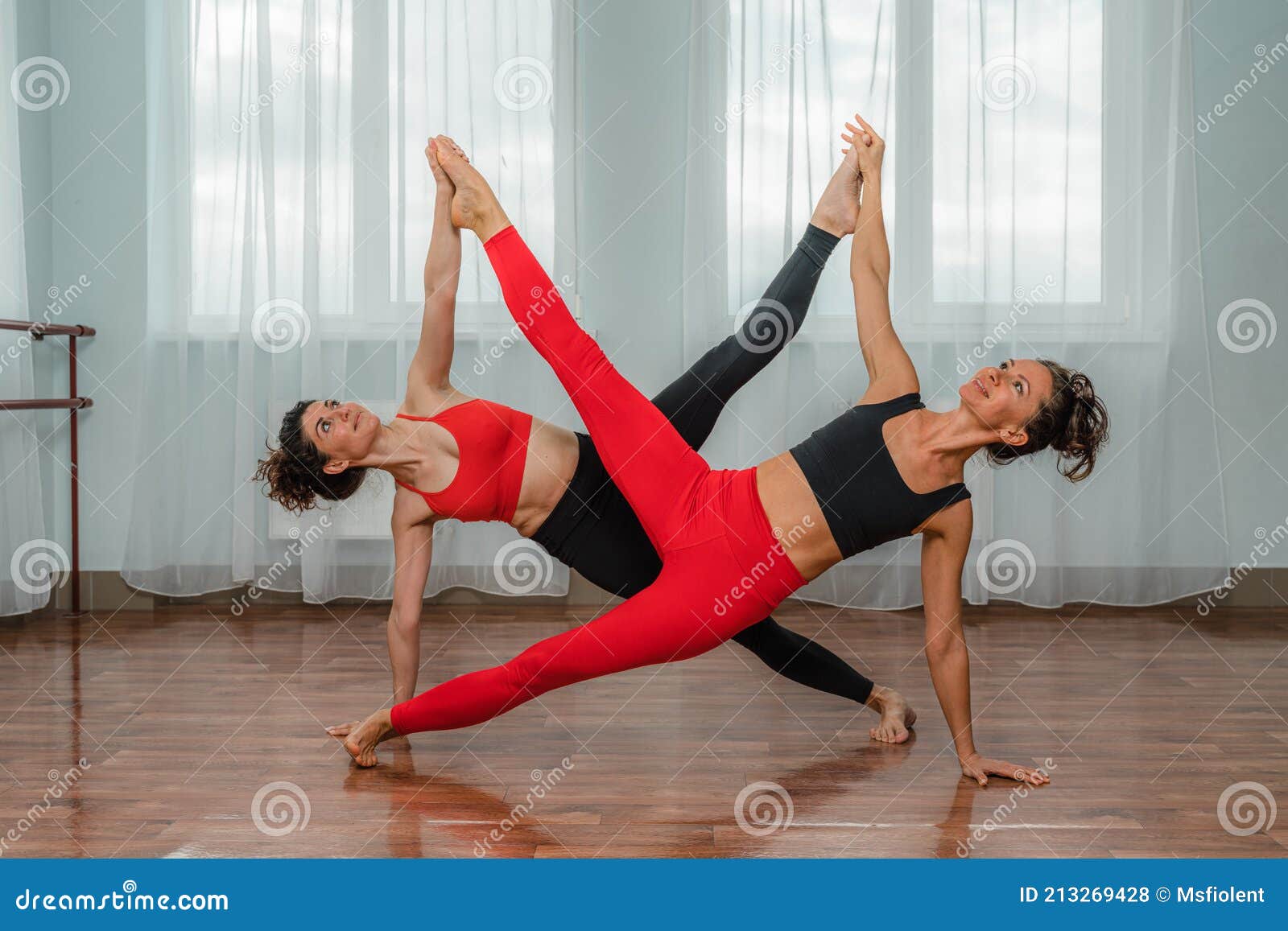 Two Attractive Athletic Girls are Practicing Asana Yoga Pose in