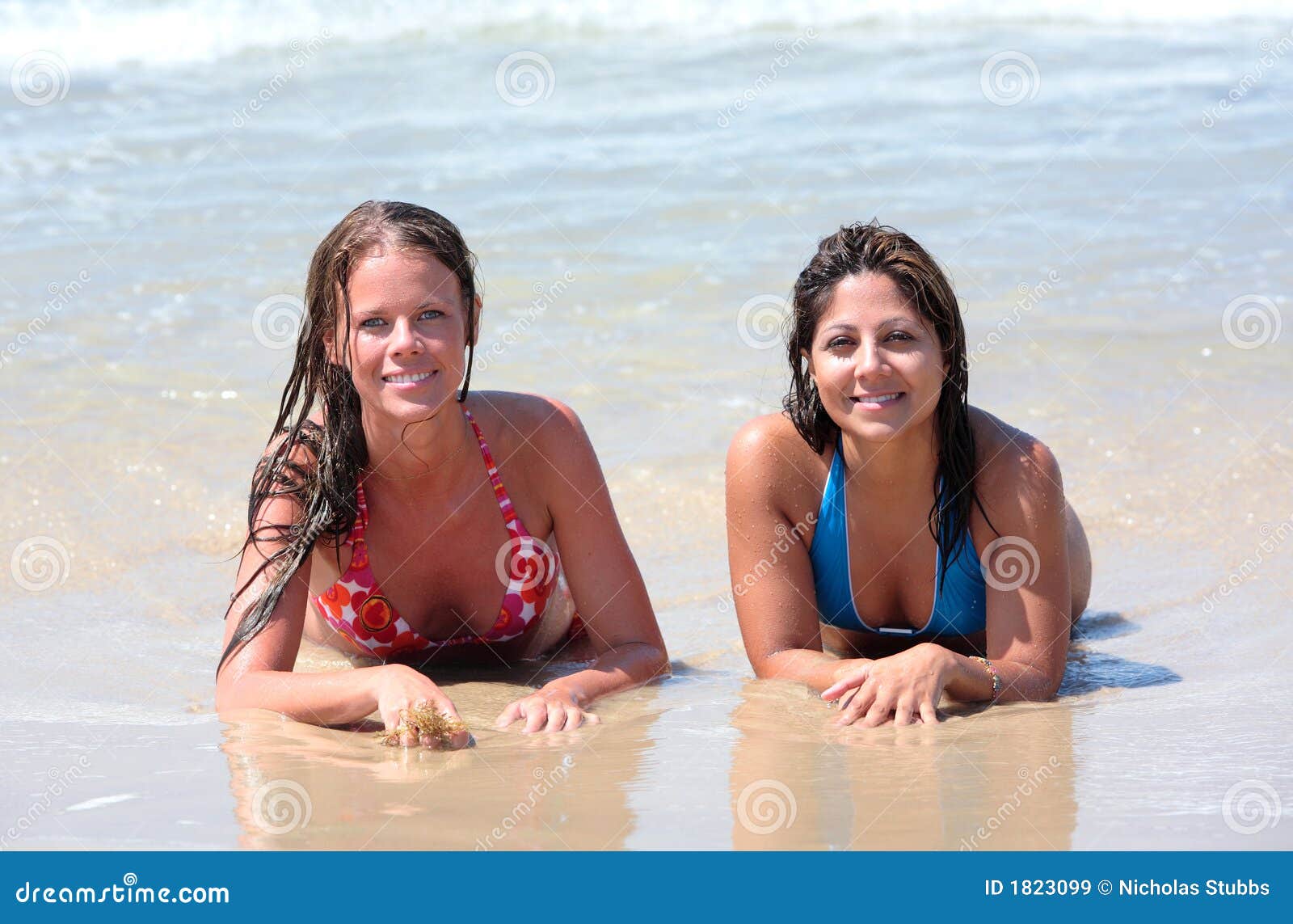 Two Attractive Young Women Lying on a Sunny Beach Near the Water Stock Image