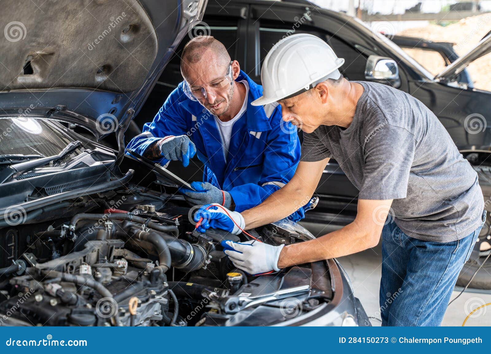 Two Auto Mechanics Using a Computer Measuring Device To Check the Car